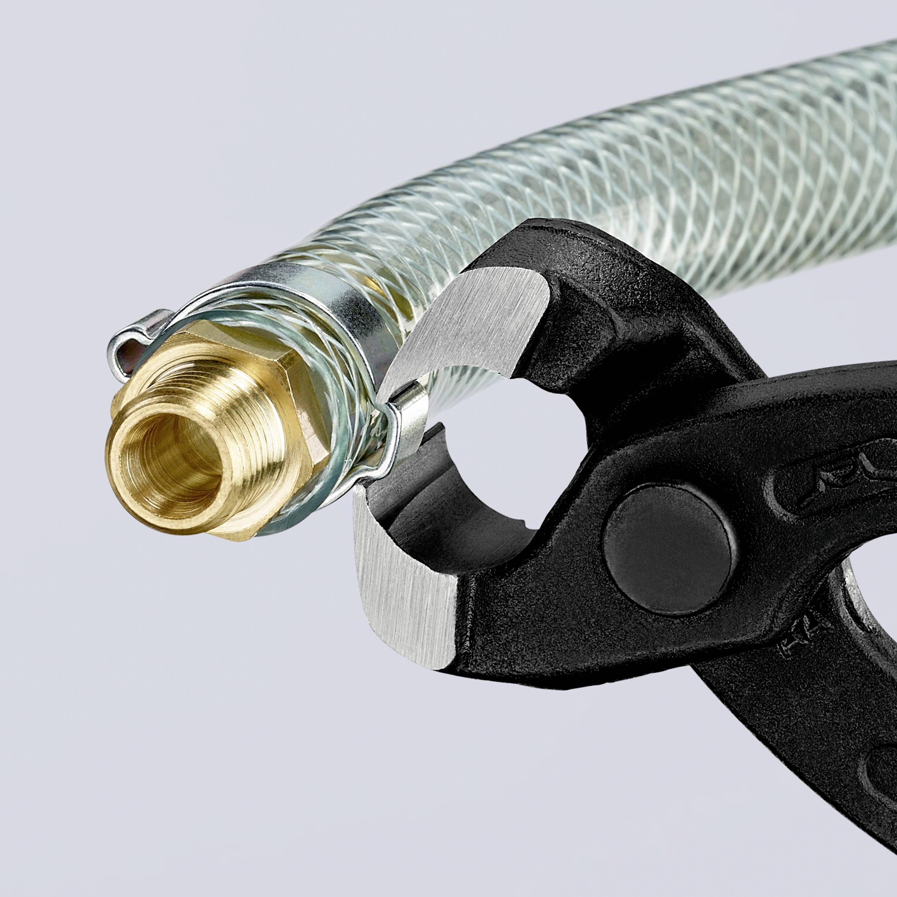 Eine Zange schneidet einen flexiblen Metallschlauch mit Messinganschluss.