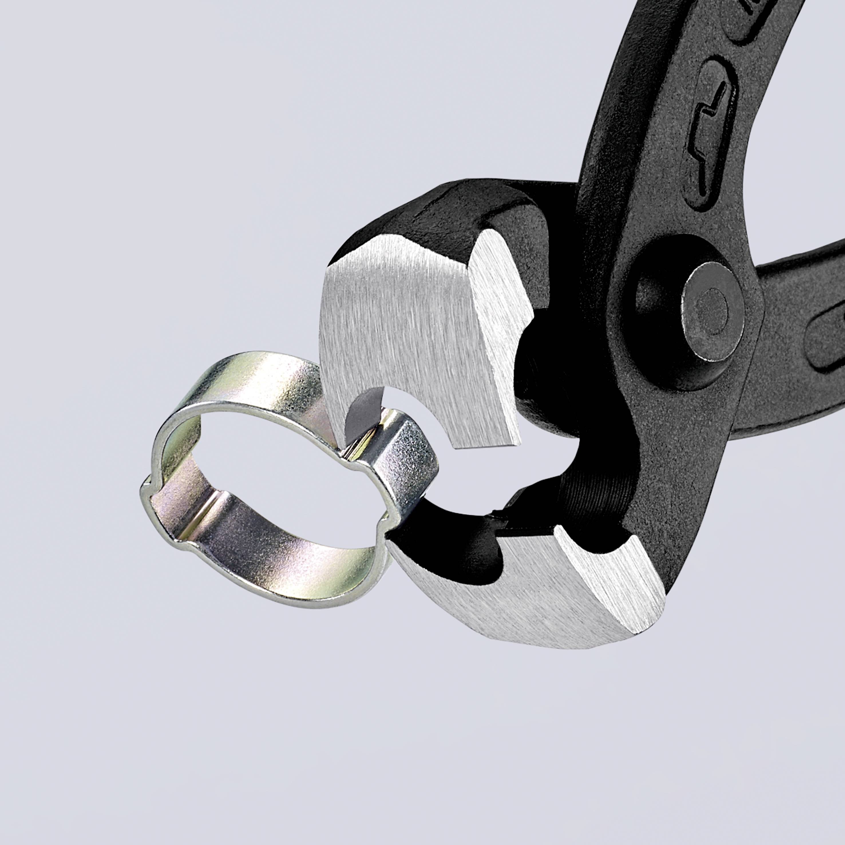 Eine Zange öffnet eine Metallschelle, die in den Backen gehalten wird.
