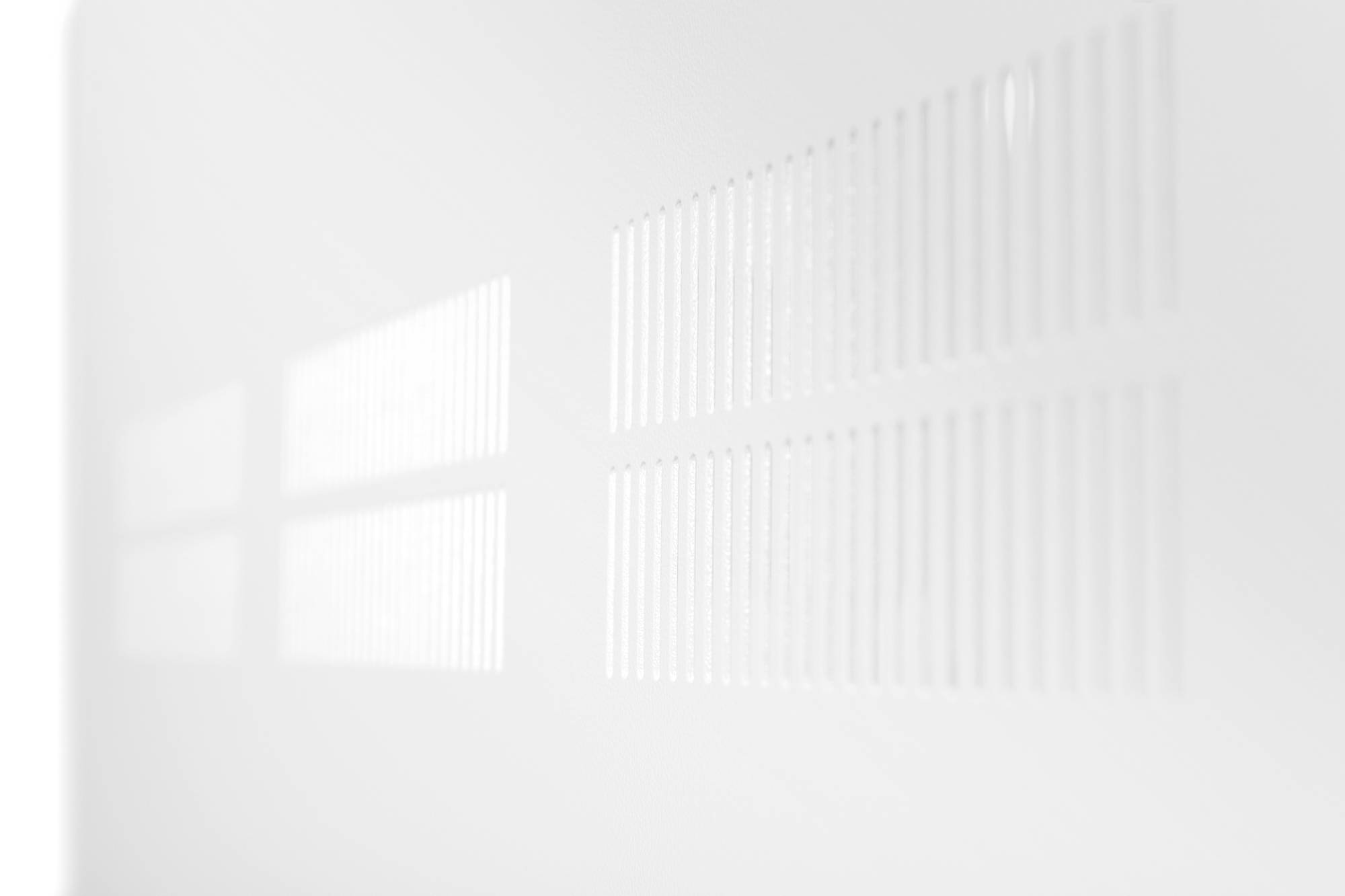 Weiße, abstrahierte Darstellung eines unscharfen Rasters mit parallelen Linien, die durch Licht auf einer Oberfläche projiziert werden.