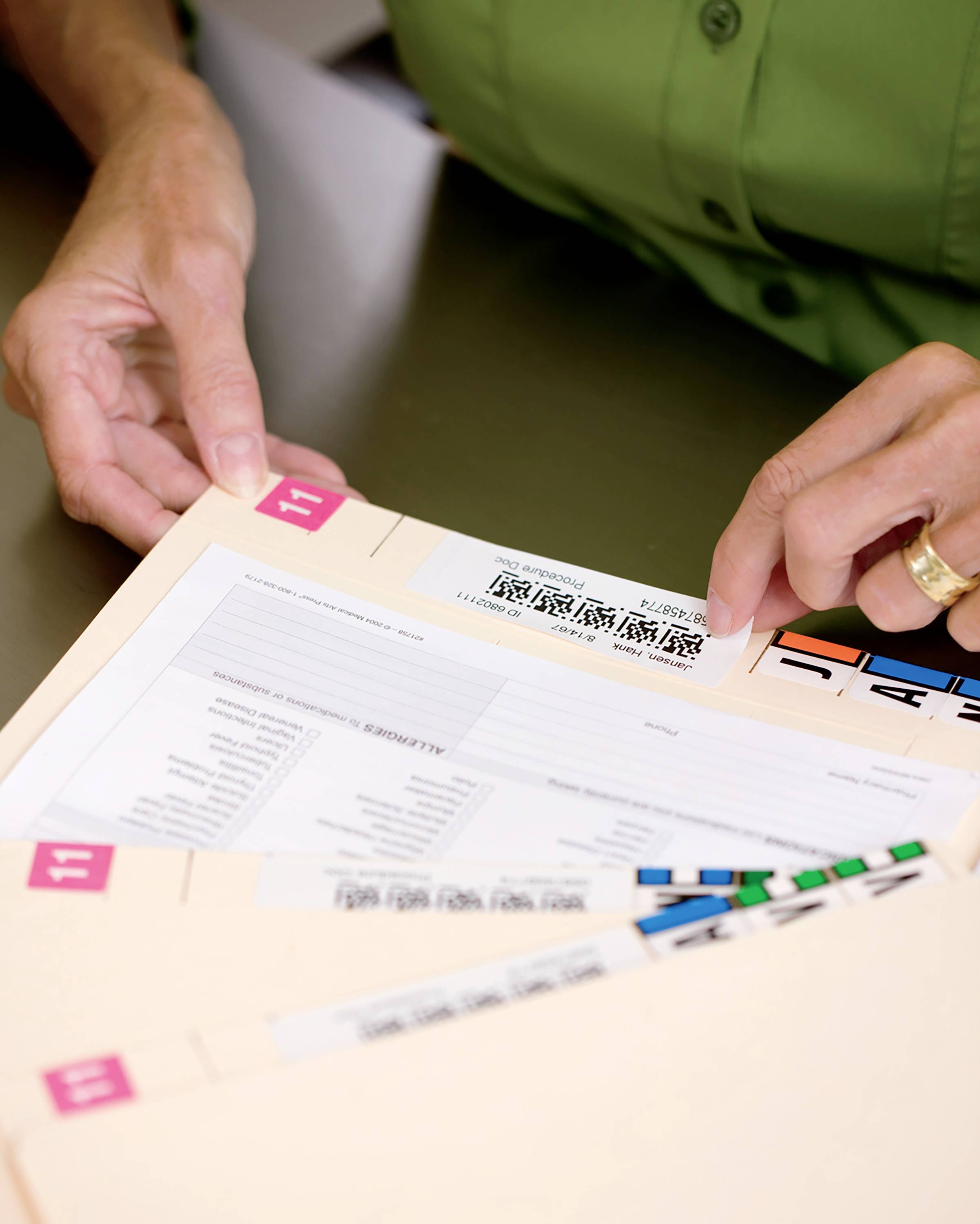 Person blättert durch Akten mit asiatischen Schriftzeichen auf Etiketten. Hände in Nahaufnahme, Fokus auf Dokumente.