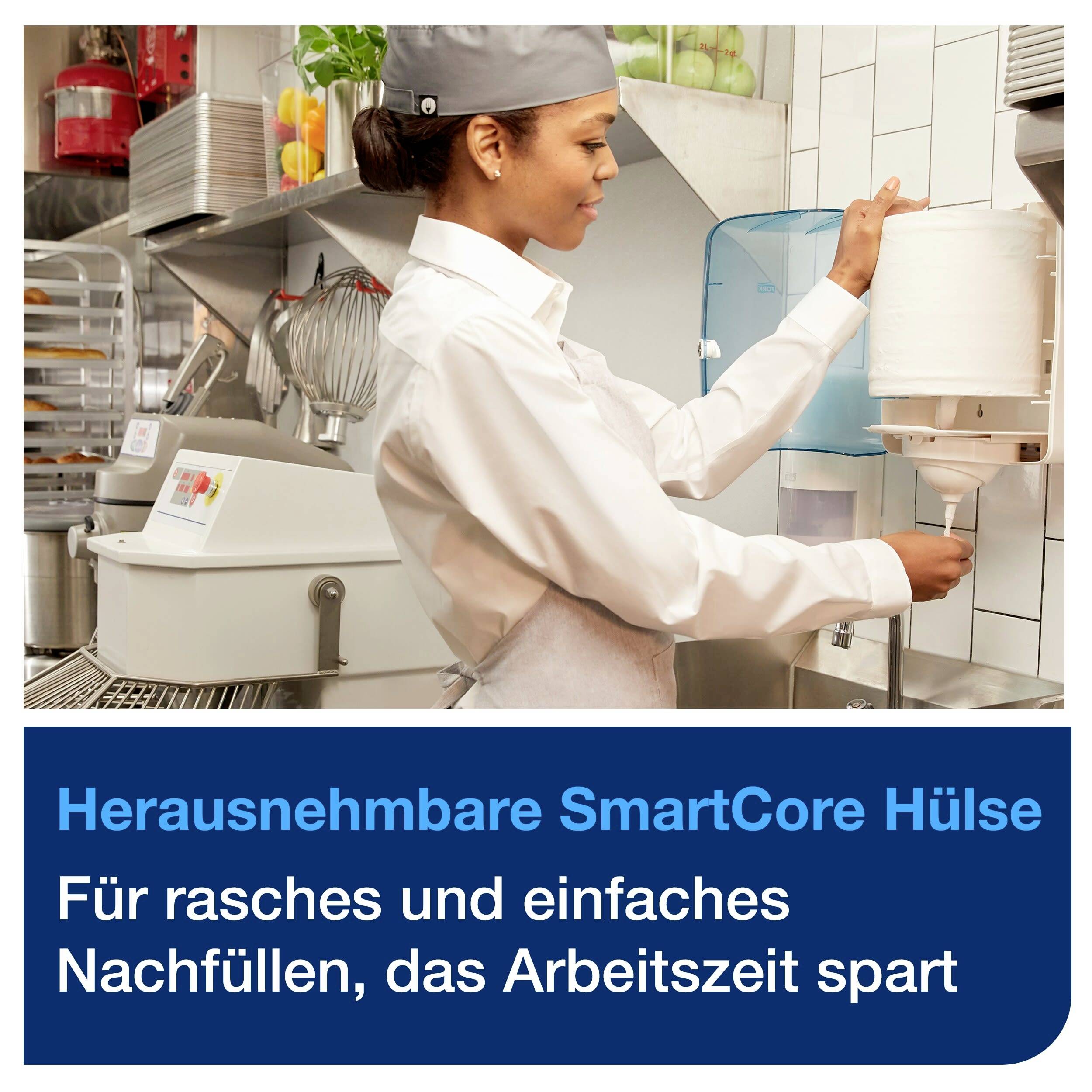 Eine Person in Arbeitskleidung wechselt eine Papierrolle in einer Küche. Text unten: 'Herausnehmbare SmartCore Hülse. Für rasches und einfaches Nachfüllen, das Arbeitszeit spart'.