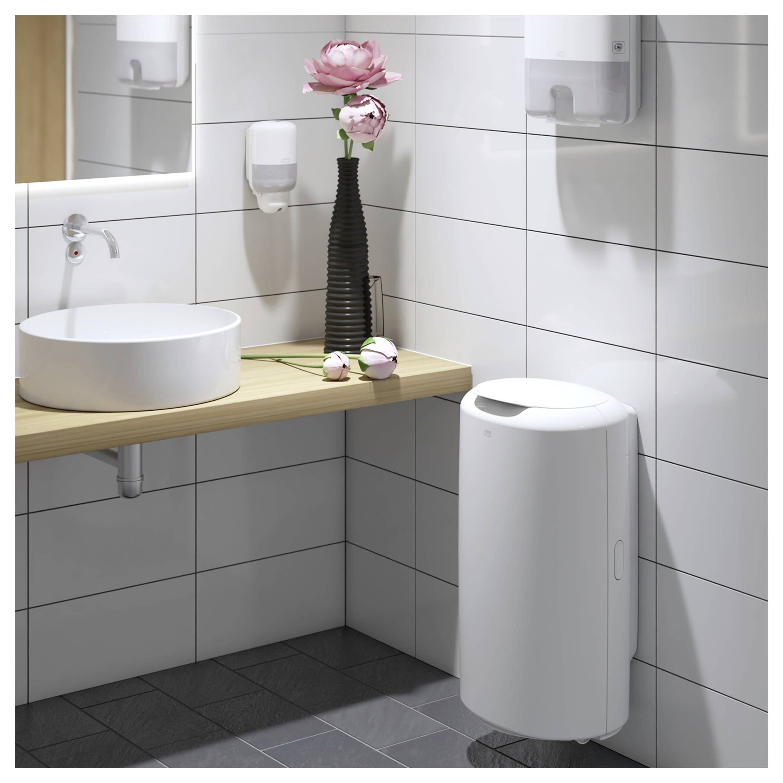 Modernes Badezimmer mit weißem Aufsatzwaschbecken, Holzablage, Wandspiegel, rosa Blumen und einem wandmontierten Mülleimer.