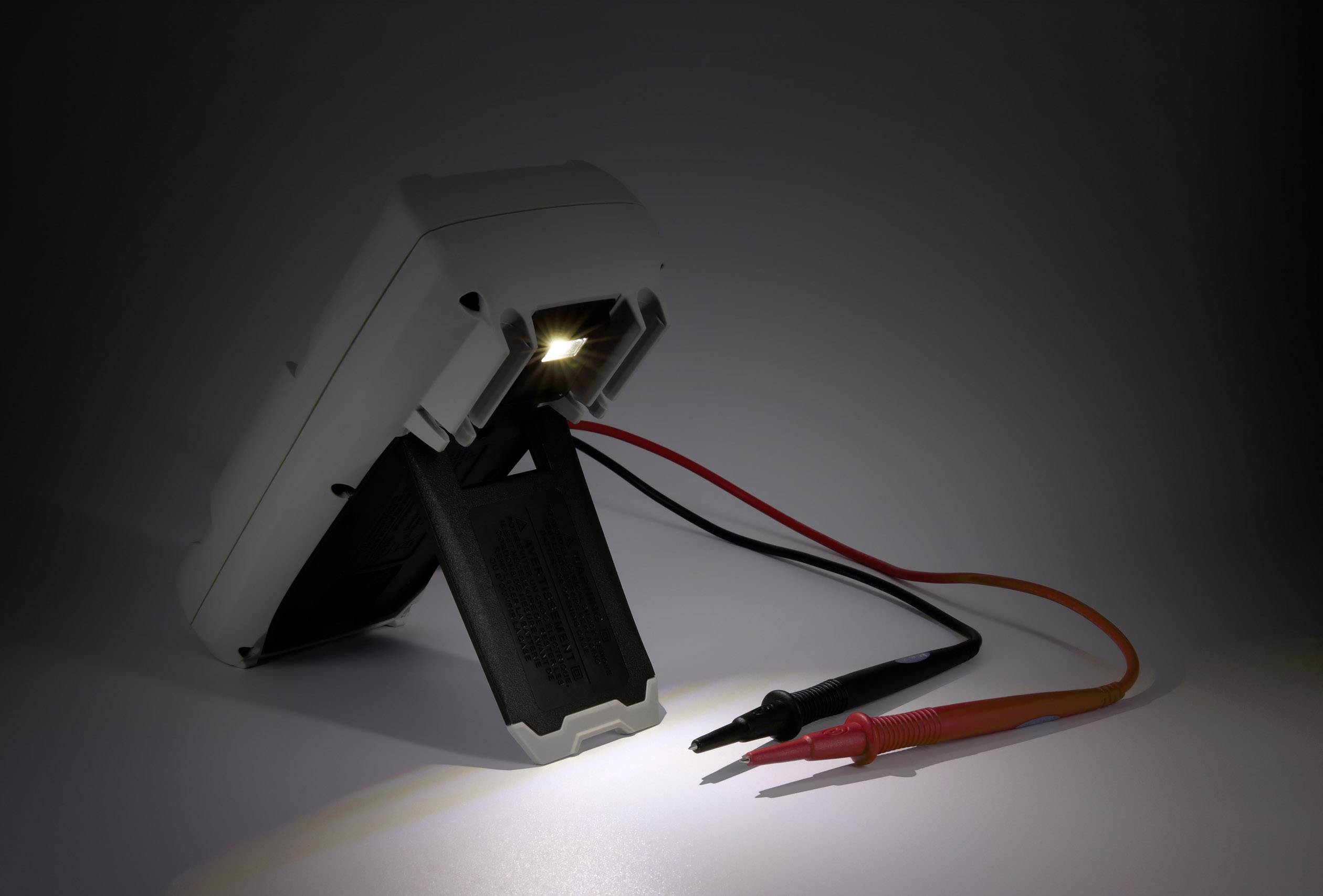 Ein digitales Multimeter zeigt den Anzeigebereich and den Messleitungen, die an das Gerät angeschlossen sind, mit Beleuchtung.