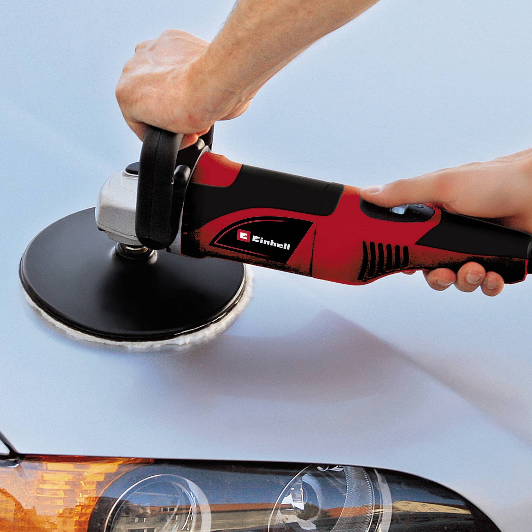 Eine Hand poliert eine Autooberfläche mit einer elektrischen Poliermaschine, um den Glanz der Fahrzeuglackierung zu verbessern.