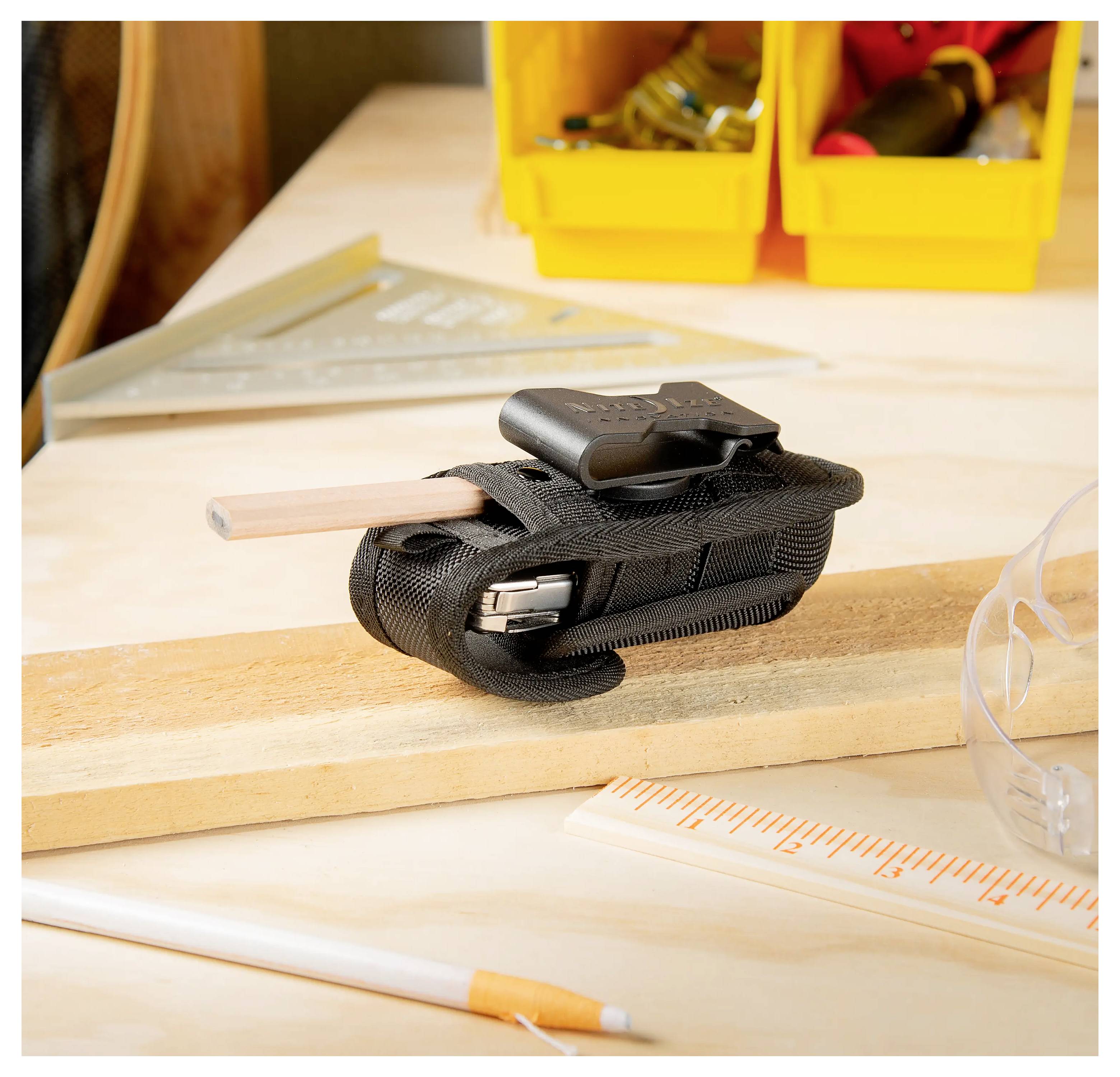 Ein Anspitzer, der an einem schwarzen Gehäuse befestigt ist, steht auf einem Holzbrett, neben einem gelben Aufbewahrungskasten und einem Lineal. Bausetting.