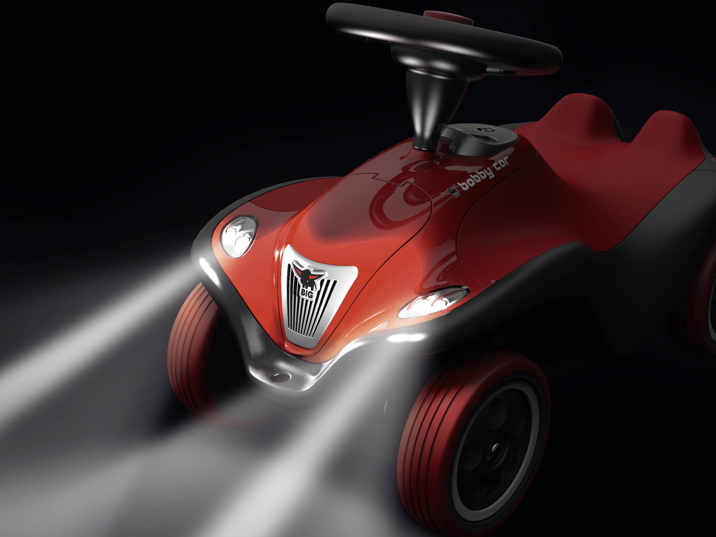 Ein rotes Spielzeugauto mit leuchtenden Scheinwerfern auf dunklem Hintergrund, zeigt ein modernes, aerodynamisches Design.