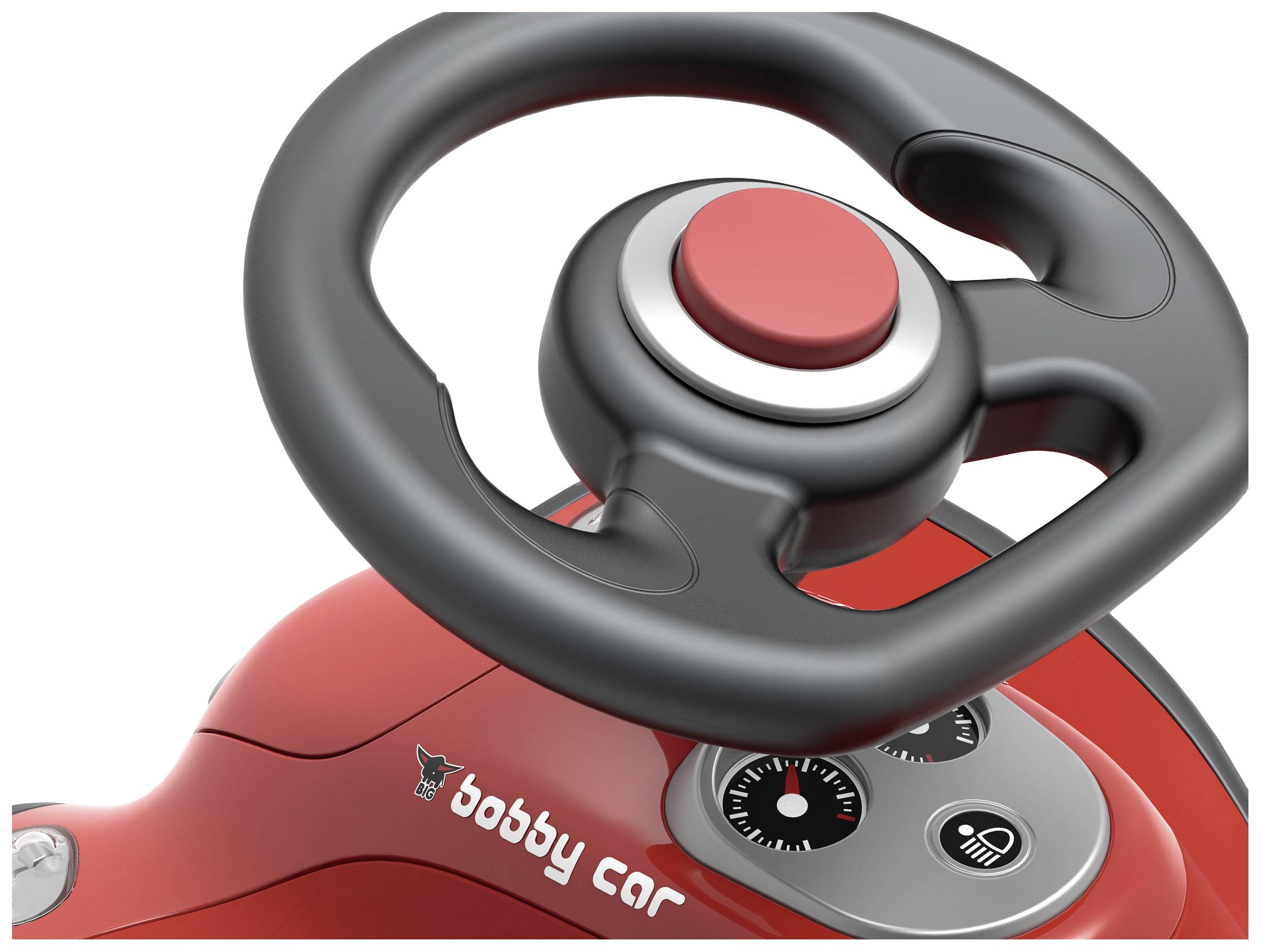 Rotes Bobby-Car-Lenkrad mit Tachoanzeige und einem großen roten Knopf, Nahaufnahme der Fahrkonsole eines Kinderfahrzeugs.
