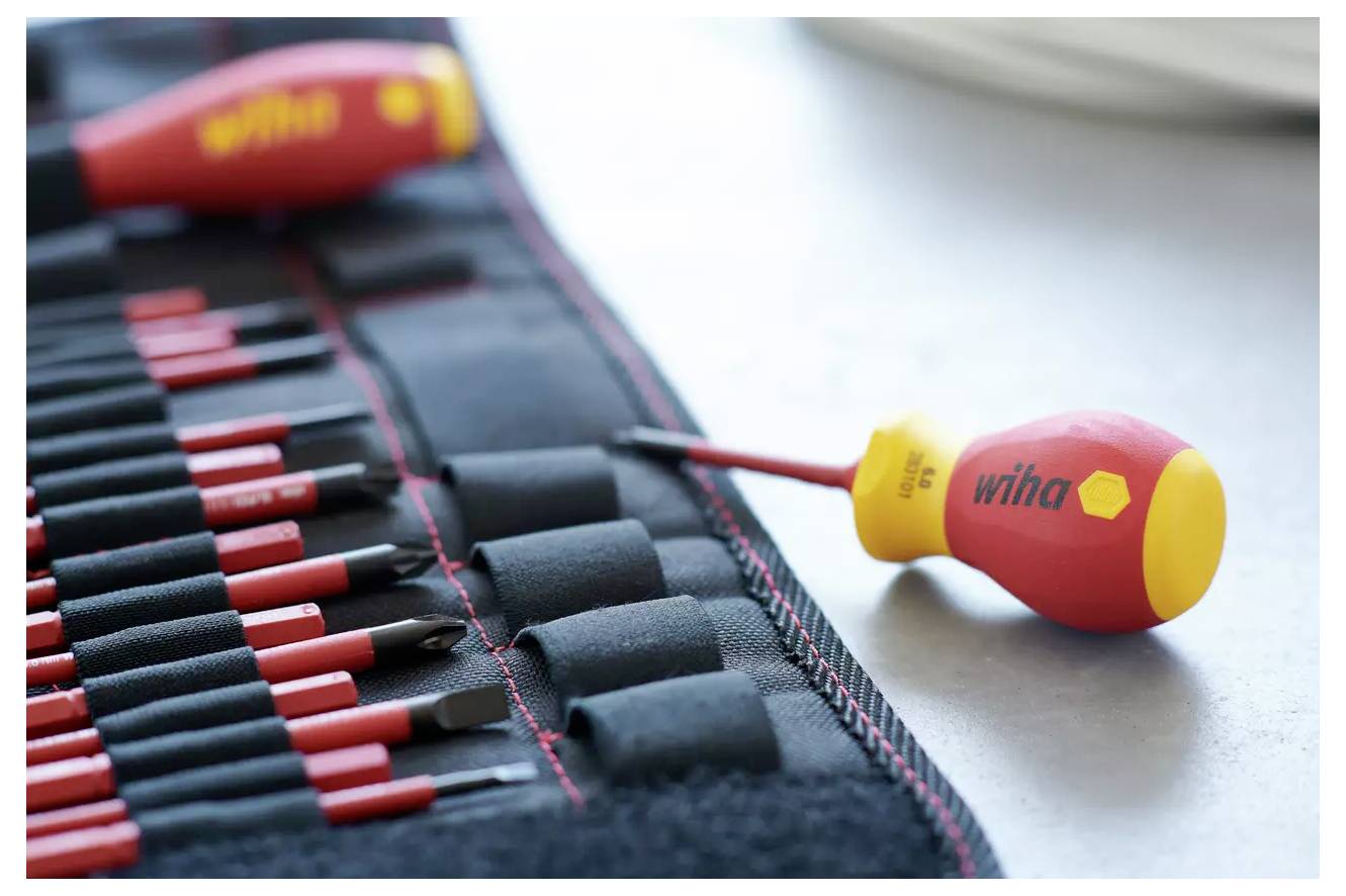 Ein Satz farbenfroher Schraubendreher auf einer Stoffmatte mit einem hervorgehobenen Werkzeug im Vordergrund. Die Werkzeuge sind ordentlich in Reihen angeordnet.