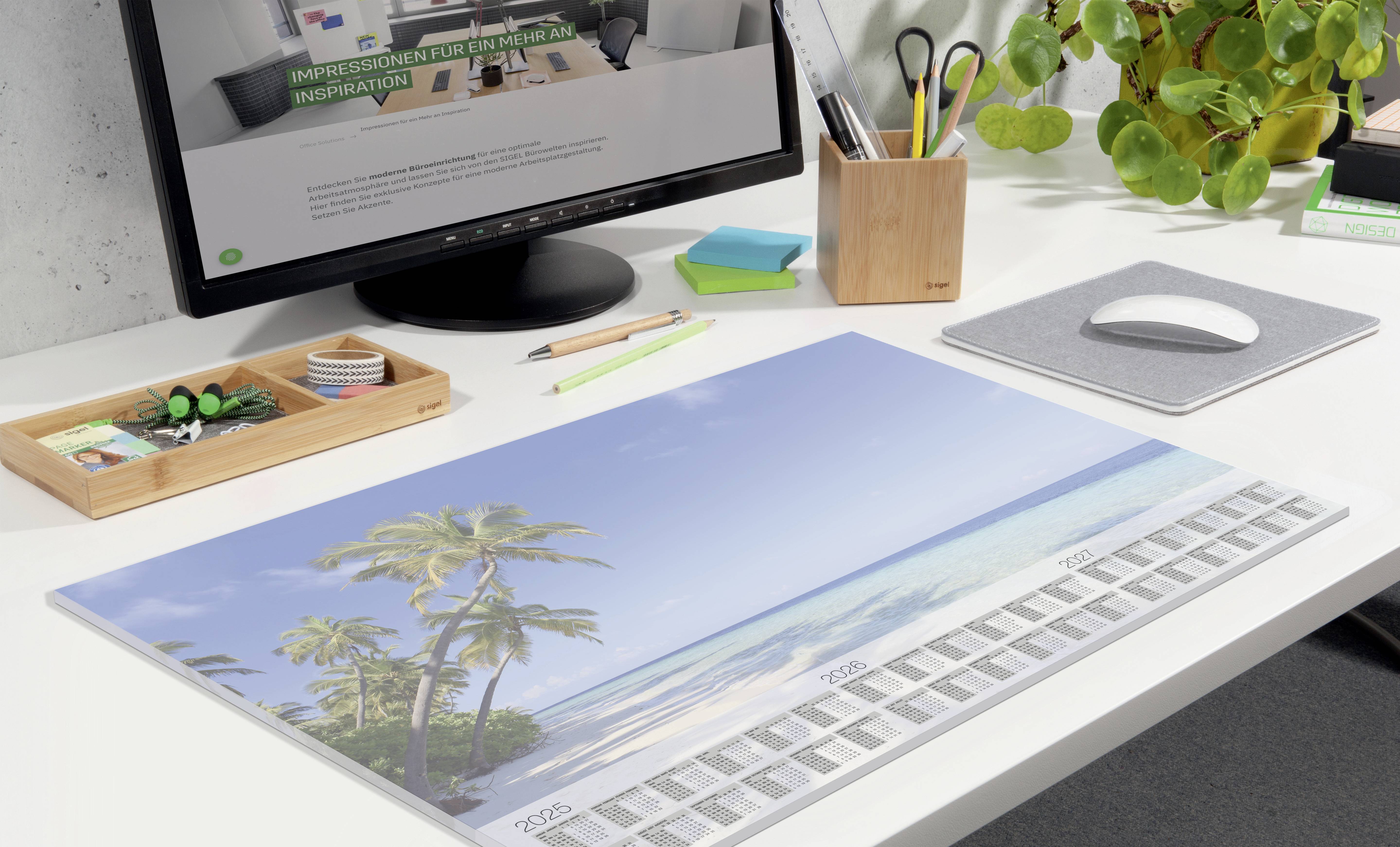 Ein Schreibtisch mit Computerbildschirm, auf dem eine Webseite angezeigt wird. Kalenderblatt mit Strandmotiv liegt auf dem Tisch.