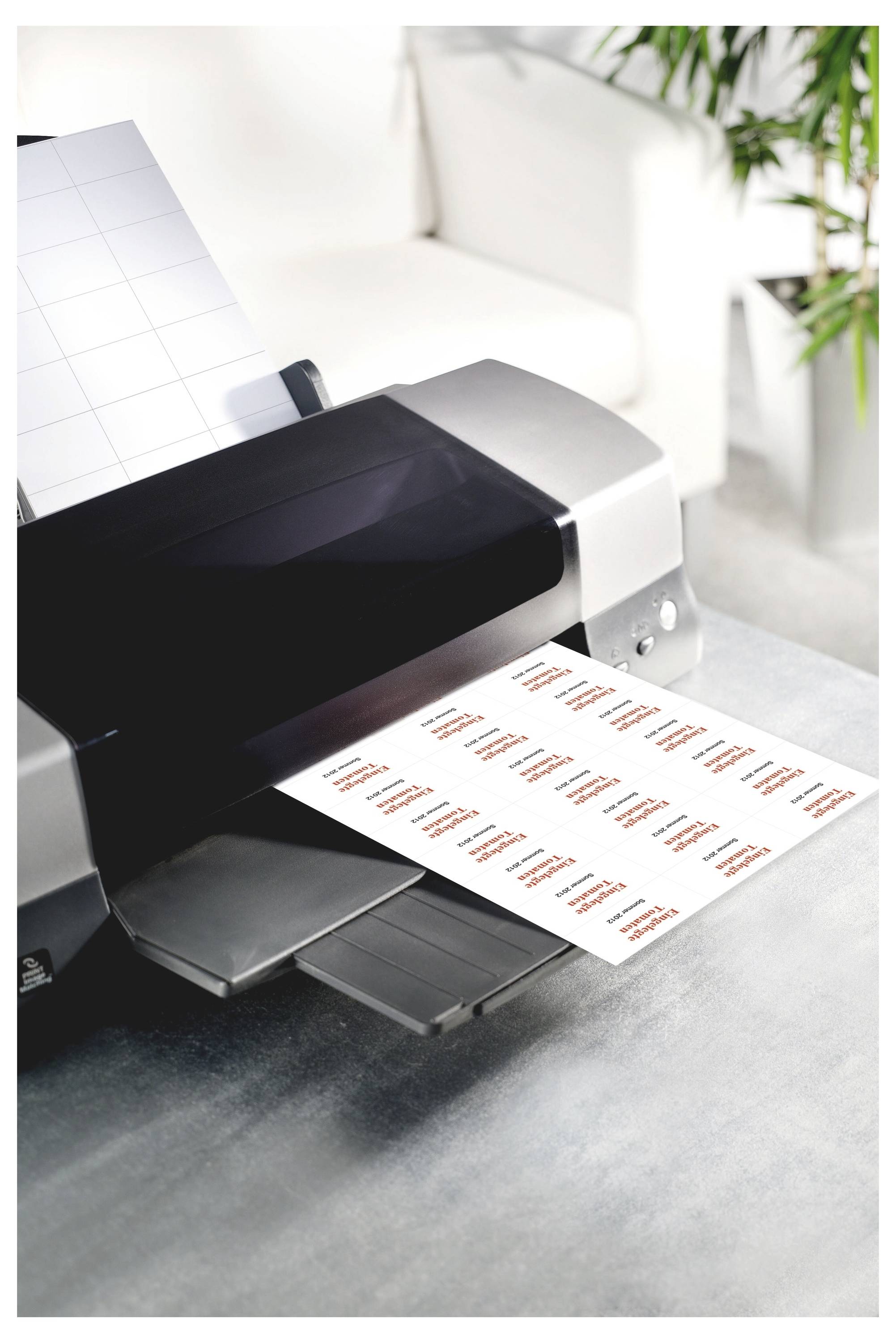 Ein Desktoprucker druckt ein Blatt mit Etiketten mit orangem Text auf das Ausgabefach.