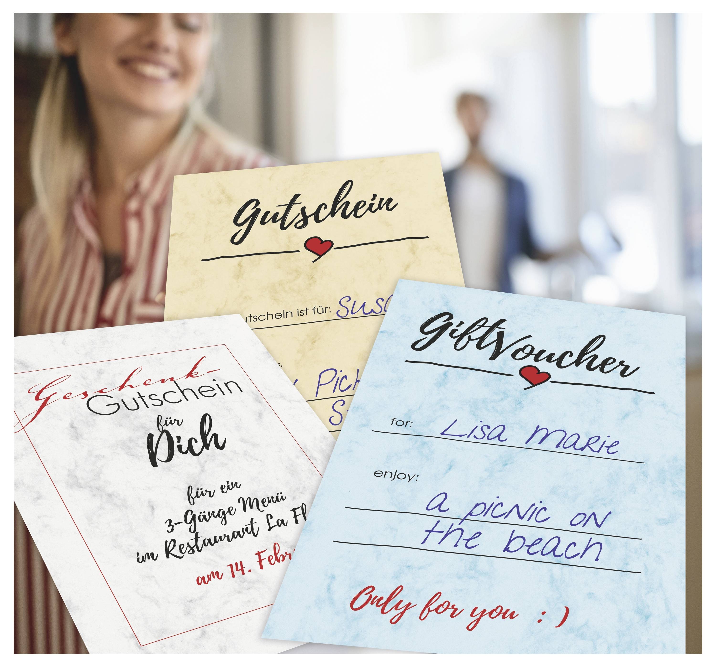 Drei handschriftliche Geschenkgutscheine, die von einer lächelnden Frau hochgehalten werden, darunter einer für Lisa Marie für "ein Picknick am Strand" und einer für "Pich" mit einer Restaurantkarte.