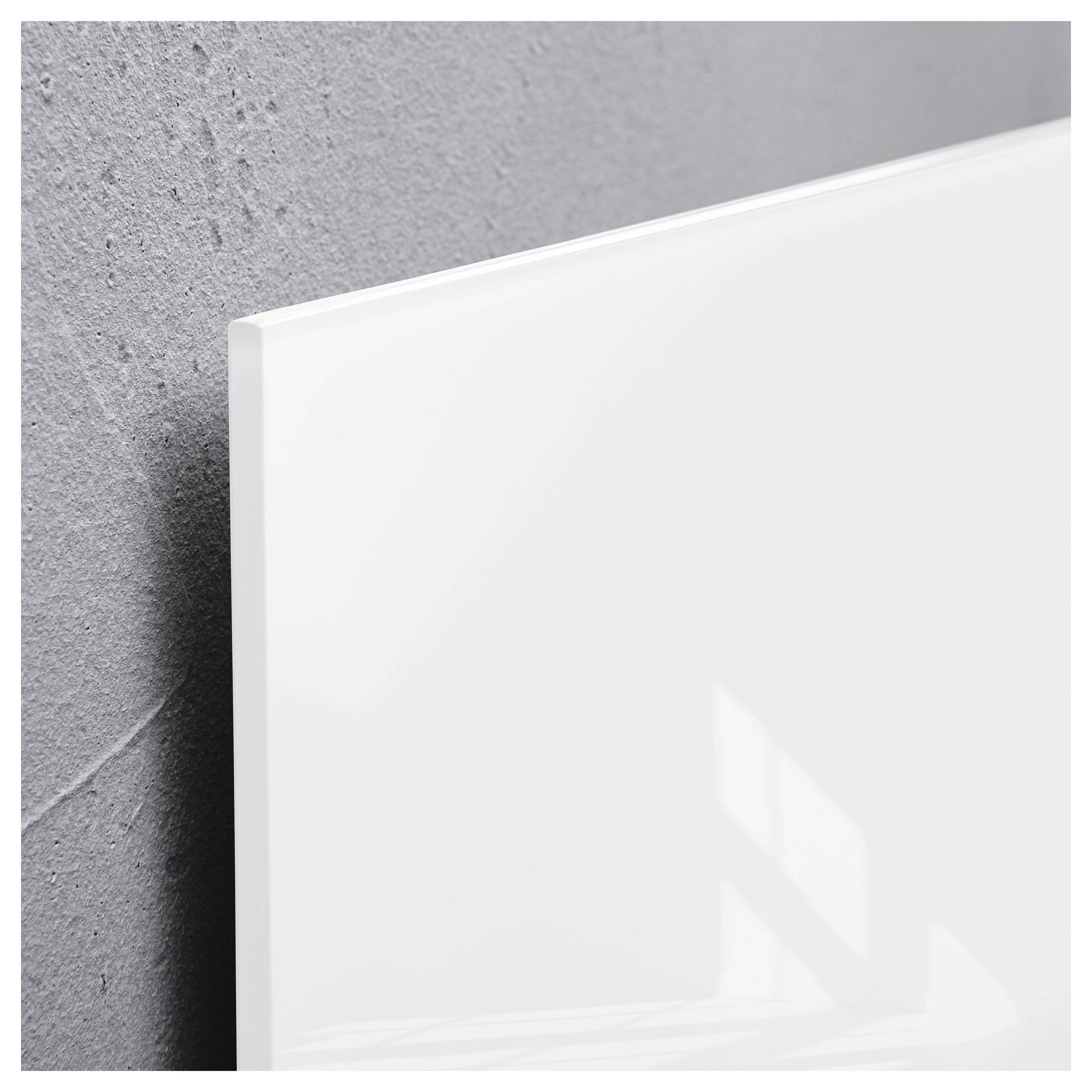 Nahaufnahme eines leeren weiß gerahmten Panels oder einer Leinwand, die an einer strukturierten grauen Wand lehnt, mit weichen Lichtreflexionen.