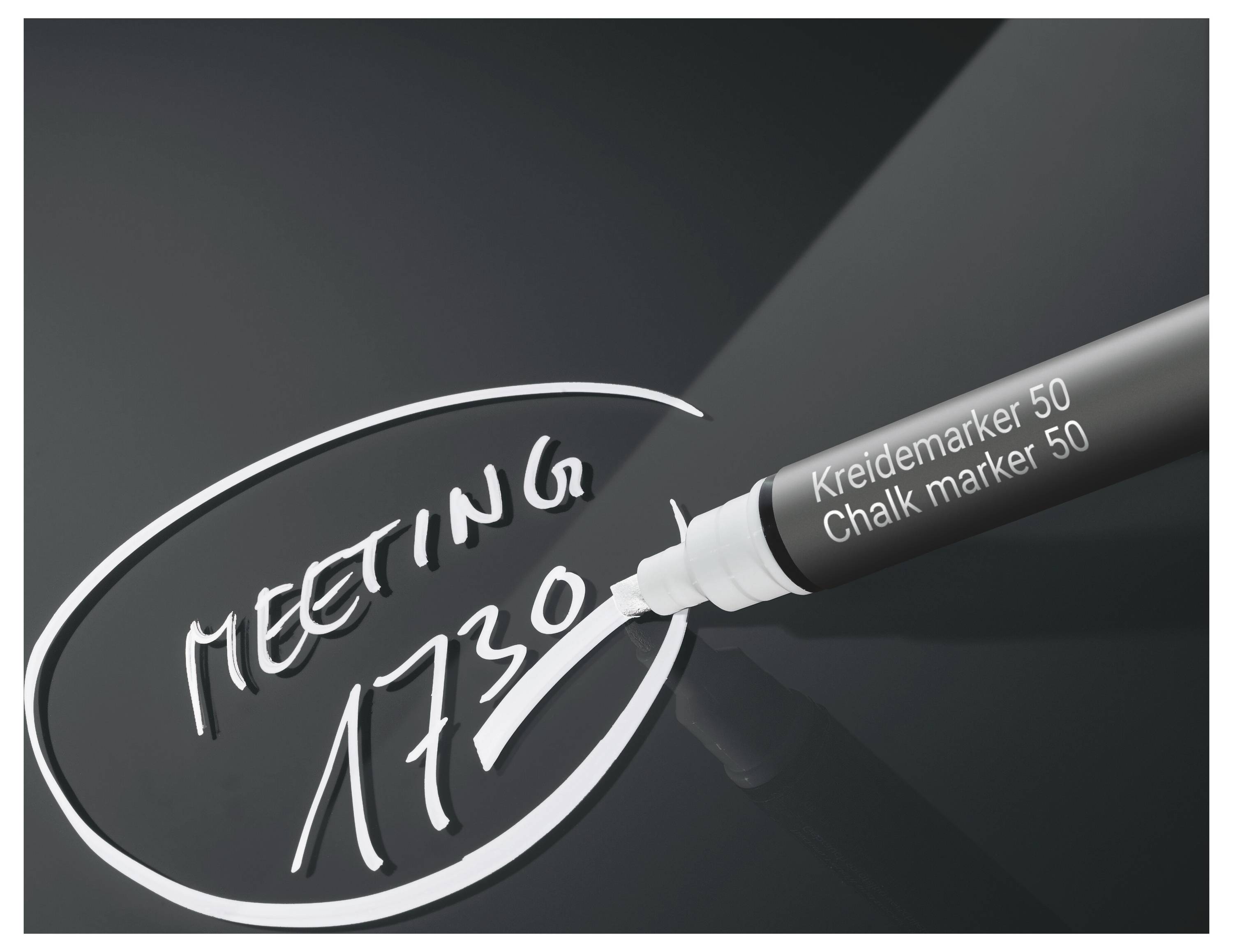 Schwarze Kreidemarkerstift-Schrift „MEETING 1730" in einem weißen Oval auf einer dunklen Tafel, mit der Markerspitze sichtbar auf der rechten Seite.