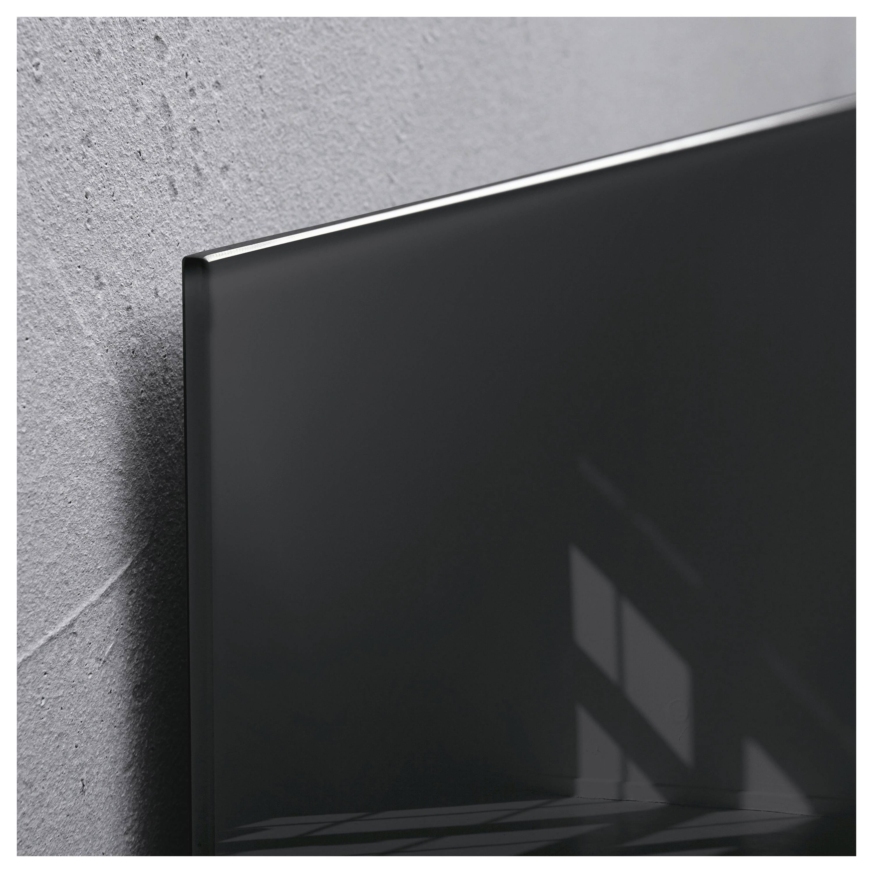 Nahaufnahme eines dünnen schwarzen Flachbildfernsehers oder Monitors, der an einer grauen strukturierten Wand montiert ist, mit Fensterlichtspegelungen auf dem Bildschirm.