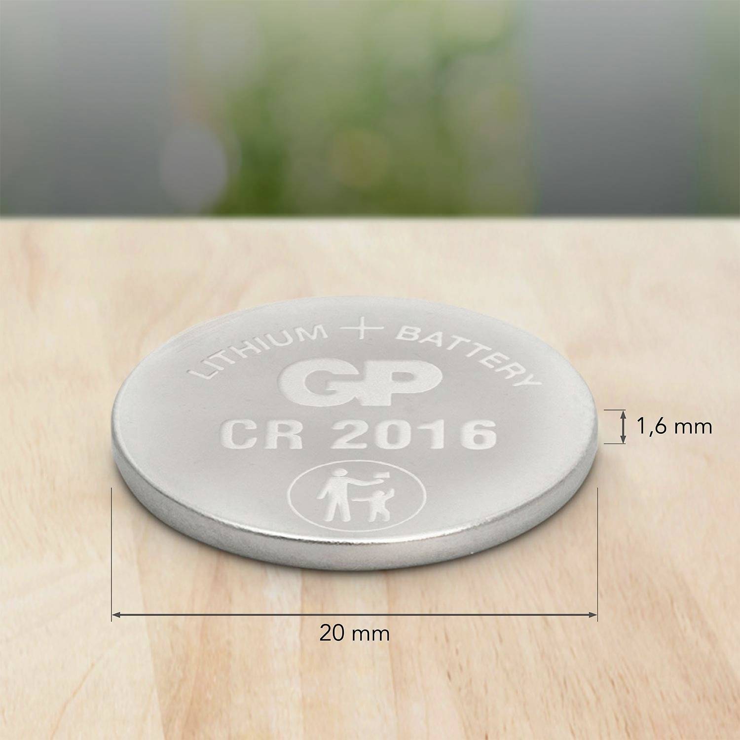 Silberne Lithium-Knopfzellenbatterie (CR 2016) mit Aufschrift 'GP' liegt auf Holzoberfläche, Maße: 20 mm Durchmesser, 1,6 mm Höhe.