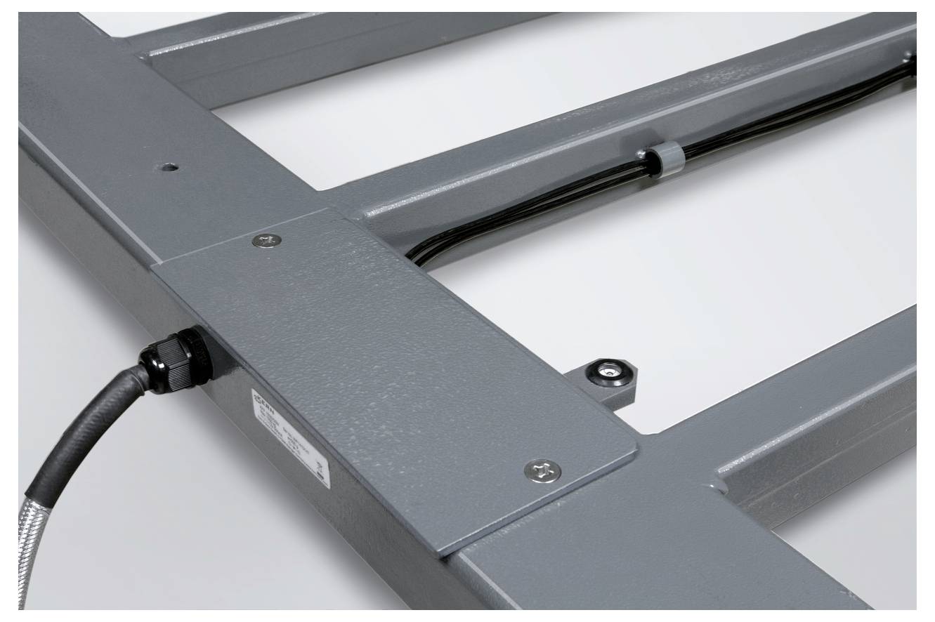 Metallrahmen mit Befestigungselementen und Kabelanschluss, wahrscheinlich Teil einer industriellen Anlage oder eines Geräts.