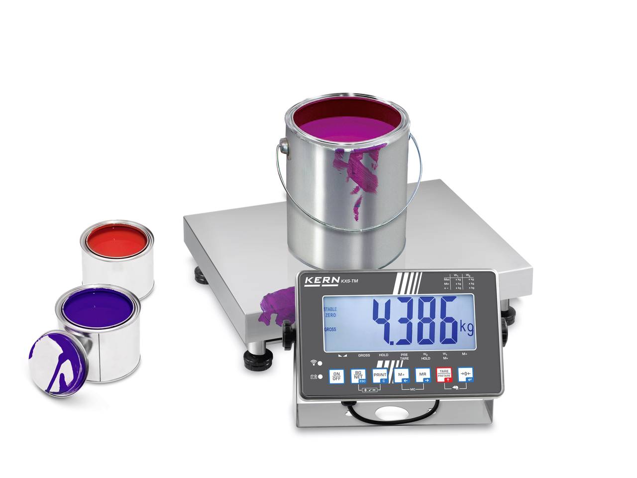 Eine digitale Waage zeigt 4,386 kg an. Ein großer Farbeimer steht darauf, zwei kleinere Eimer mit roter und violetter Farbe daneben.