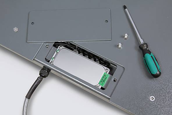 Nahaufnahme einer geöffneten Metallabdeckung mit sichtbarer Elektronik im Inneren. Ein Schraubendreher liegt daneben.