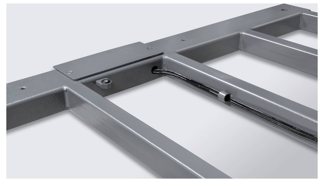 Nahaufnahme eines grauen Metallrahmens mit integrierten Kabeln, die durch eine Halterung geführt werden.