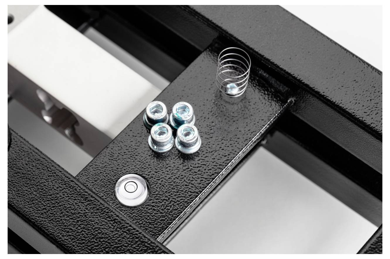 Ein schwarzes Metallgestell mit fünf Schrauben und einer Metallscheibe auf einem Teil des Rahmens.