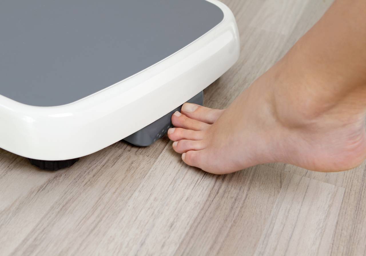 Person schaltet eine Körperwaage mit dem Zeh ein