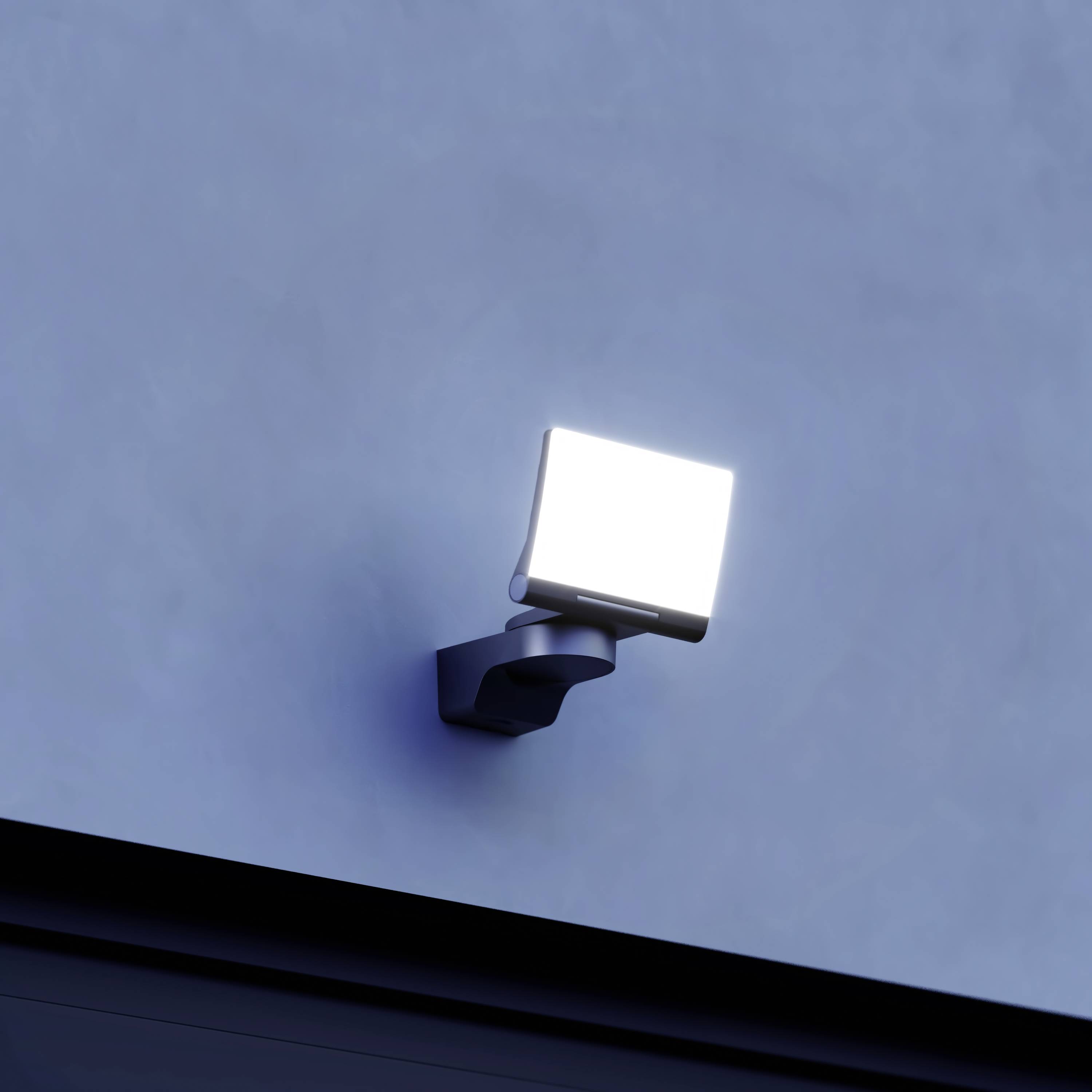 Wandleuchte mit starkem Flutlicht, montiert an einer blauen Wand, spendet helles Licht.