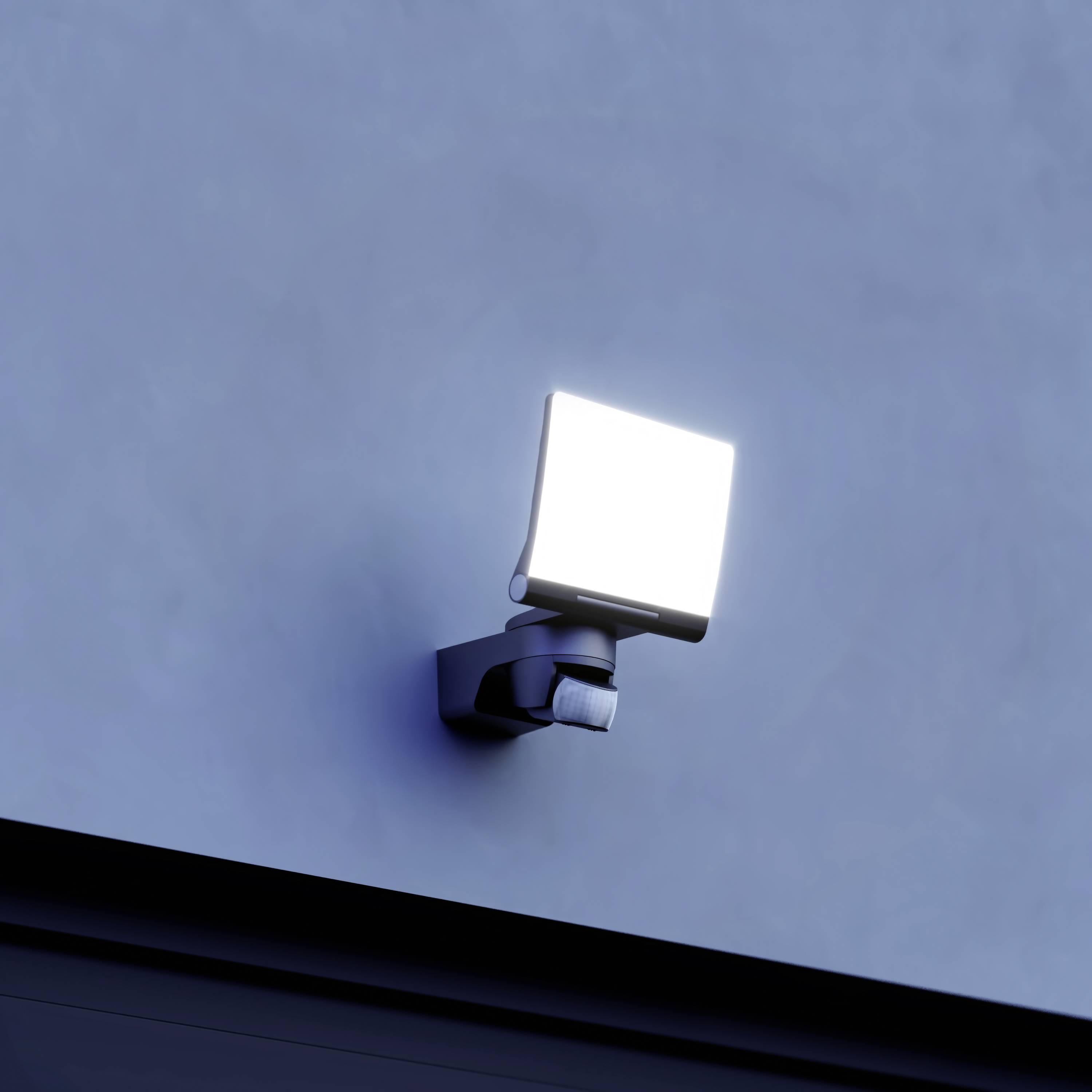 Eine leuchtende Außenlampe an einer Wand in der Dämmerung, die die Umgebung mit hellem Licht erhellt.