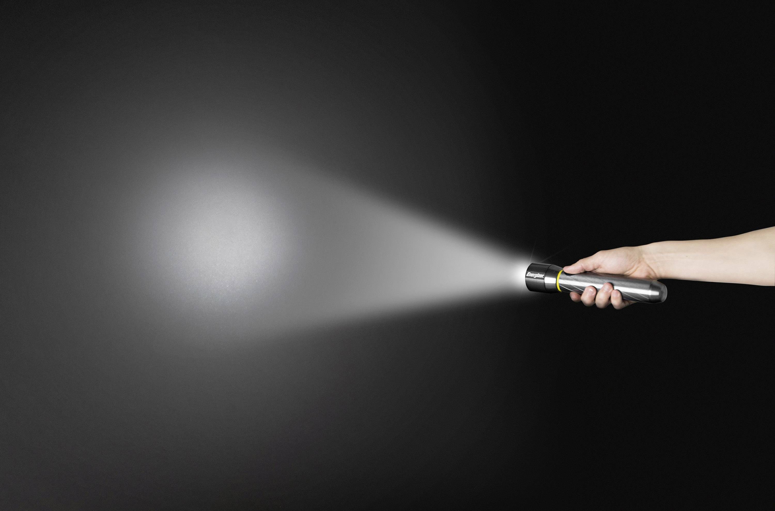 Eine Hand hält eine eingeschaltete Taschenlampe, die einen Lichtstrahl auf einen dunklen Hintergrund wirft.