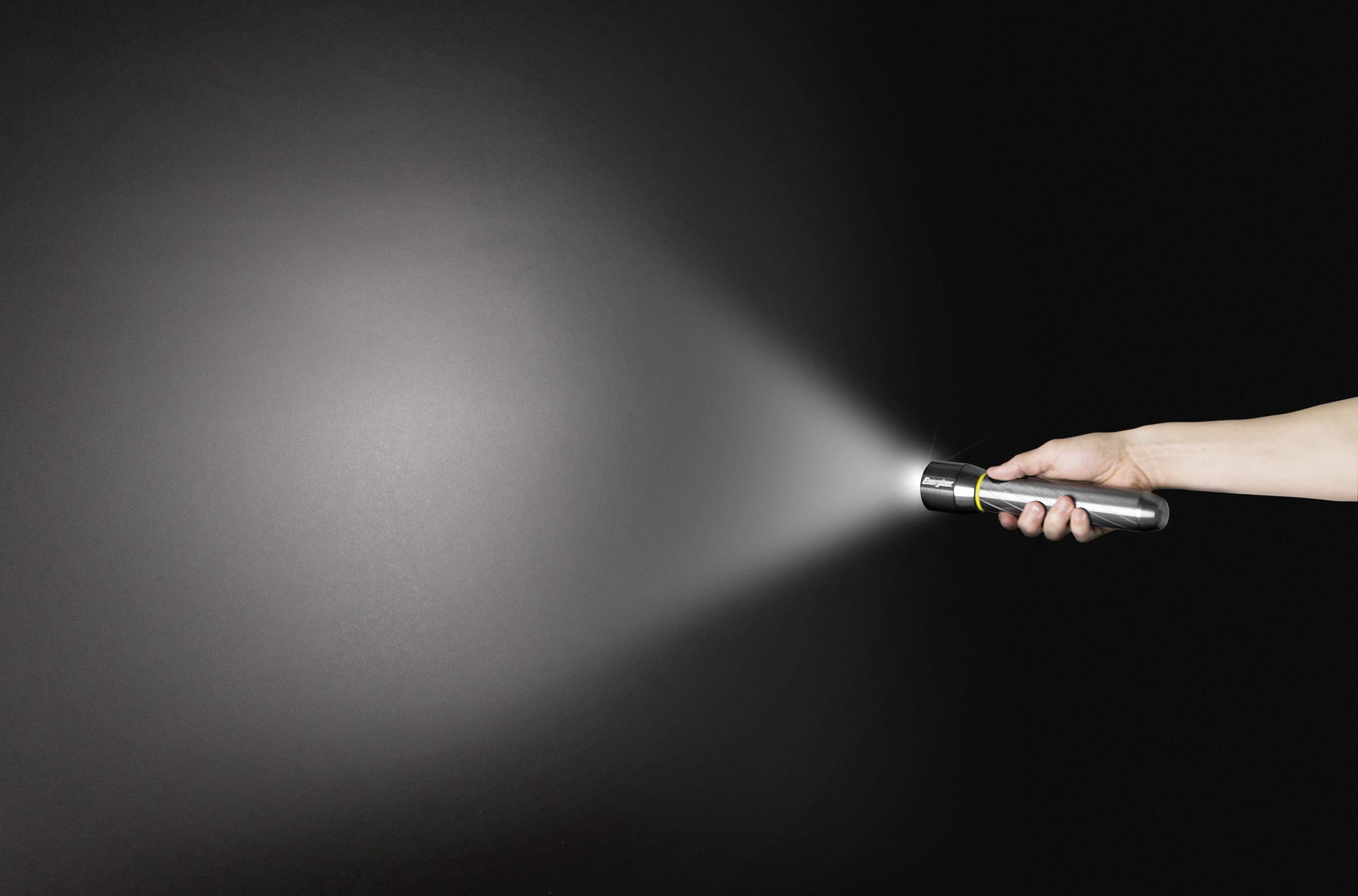 Eine Hand hält eine Taschenlampe, die in einem dunklen Raum leuchtet. Der Lichtstrahl ist klar sichtbar auf der schwarzen Wand.