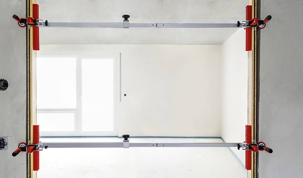 Türrahmen mit zwei Metallstützen zur Stabilisierung, im Hintergrund ein heller, leerer Raum mit einem großen Fenster.