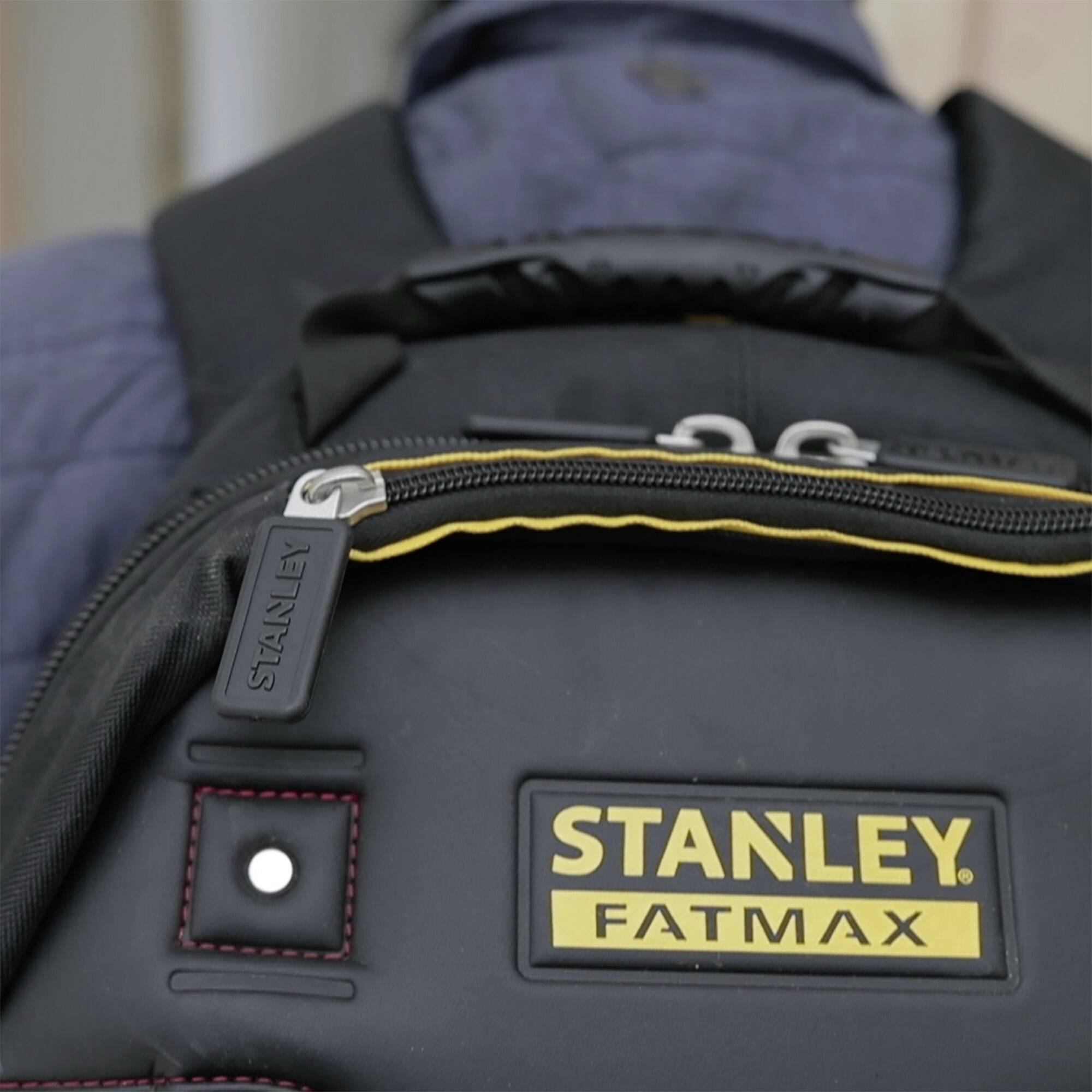 Schwarzer Rucksack mit gelbem 'STANLEY FATMAX'-Logo. Der Reißverschluss hat einen 'STANLEY'-Anhänger.