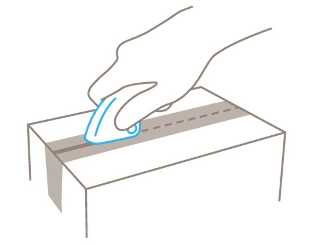 Hand hält ein Messer und schneidet einen Karton entlang einer markierten Linie auf.