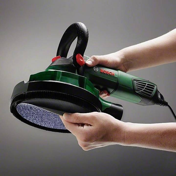 Zwei Hände halten eine Bosch-Poliermaschine mit einem großen, runden Polierkissen, bereit zur Anwendung.