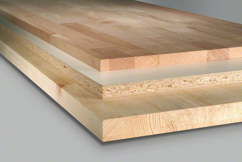 Drei unterschiedliche Holzplatten übereinander gestapelt: Oben dünnes Laminat, in der Mitte Pressspan, unten dickes Massivholz.