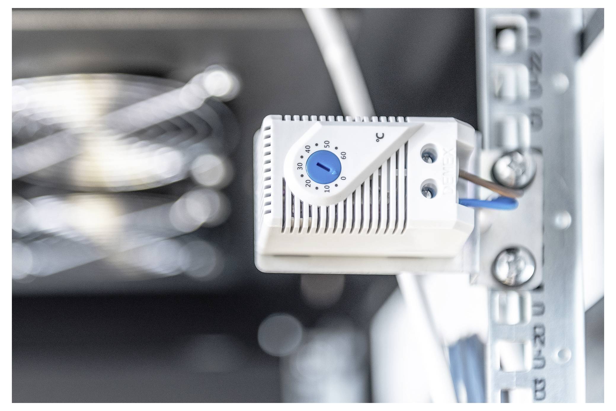 Ein Temperaturregelgerät mit einem blauen Drehknopf ist auf einem Metallrahmen montiert und zeigt ein System zur Regulierung von Umweltbedingungen an.
