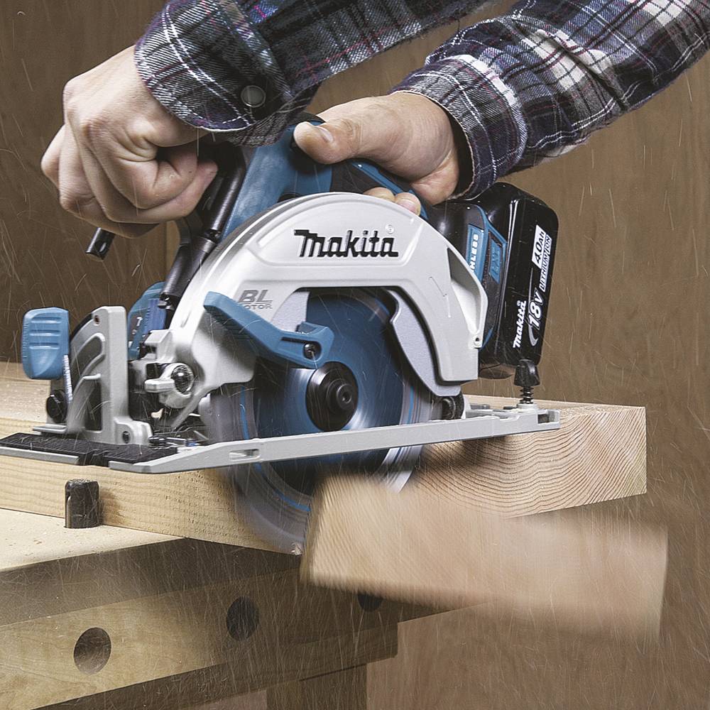 Eine Person benutzt eine blaue und silberne Handkreissäge, um ein Holzstück zu schneiden. Die Säge trägt die Marke 'Makita'.