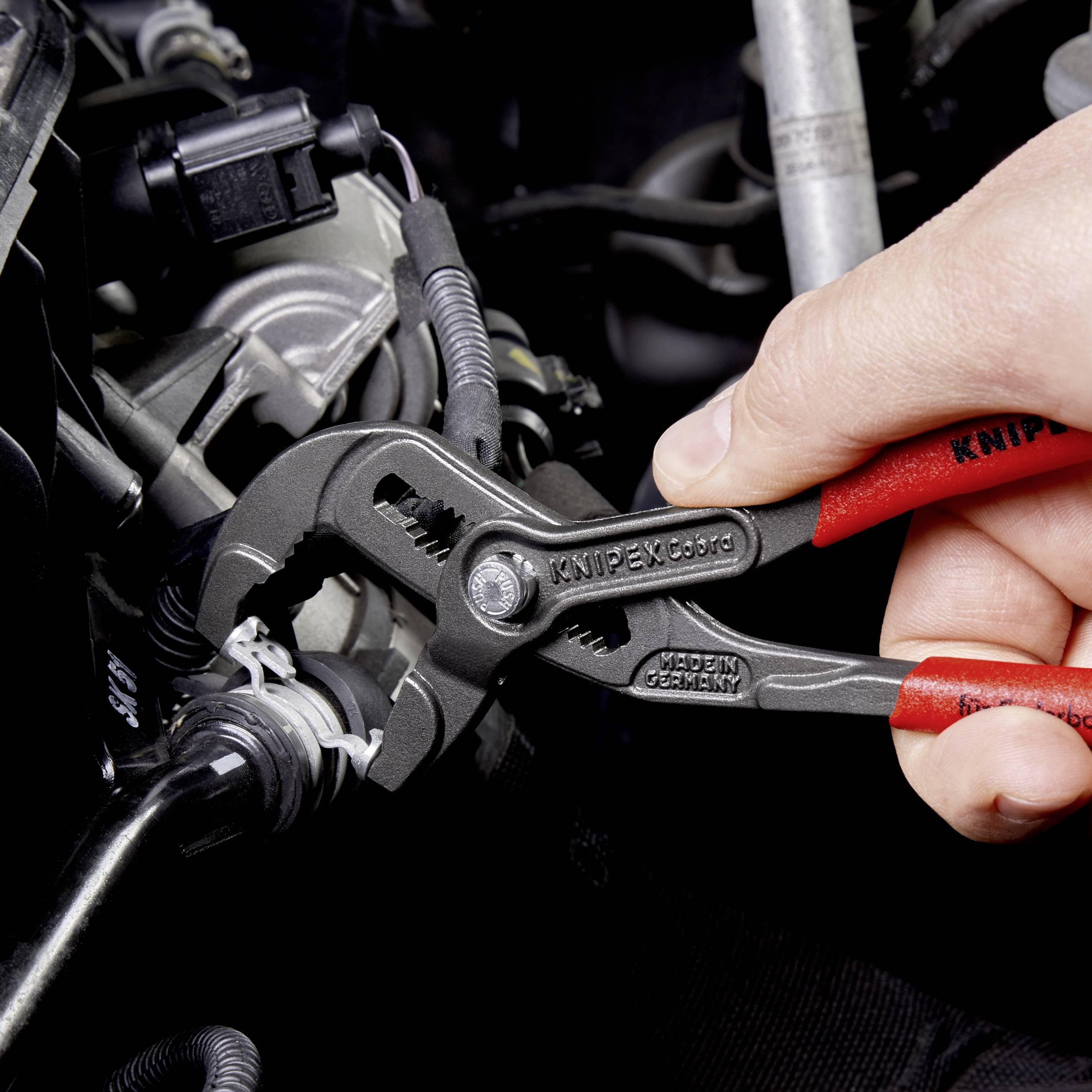 Hand hält Knipex Zange, die an einem Rohr arbeitet. Die Szene zeigt die Anwendung von Werkzeug für mechanische Arbeiten.