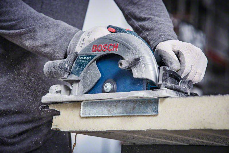 Person schneidet mit einer Handkreissäge Holz. Staub entsteht beim Sägen. Brandschrift 'Bosch' auf der Säge erkennbar.