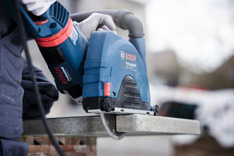 Eine Person schneidet mit einer elektrischen Bosch-Handkreissäge einen Betonblock. Die Umgebung ist unscharf.
