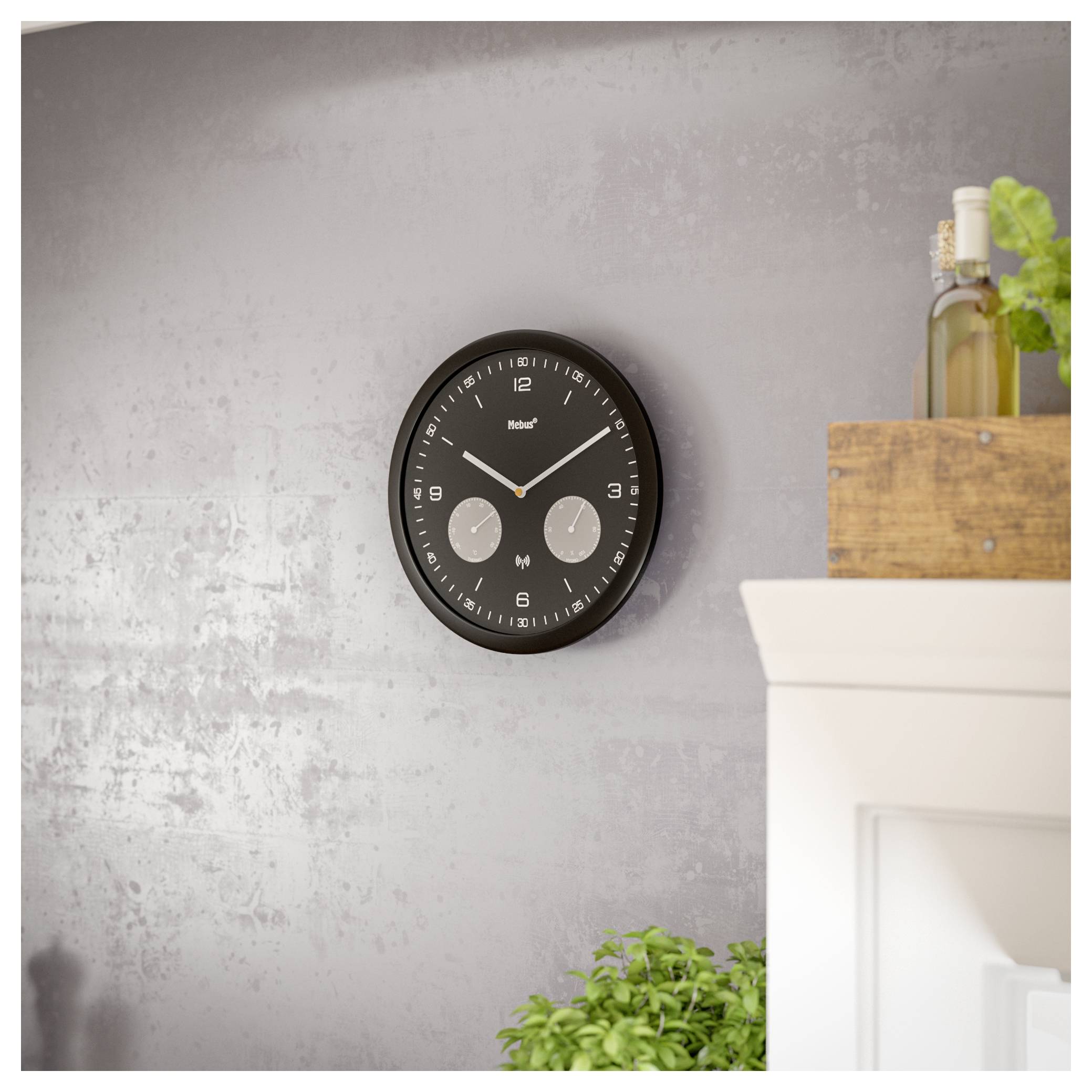 Eine Wanduhr mit schwarzem Rahmen und zwei kleineren Zifferblättern, die sowohl Ortszeit als auch internationale Zeiten anzeigt, hängt an einer strukturierten grauen Wand.