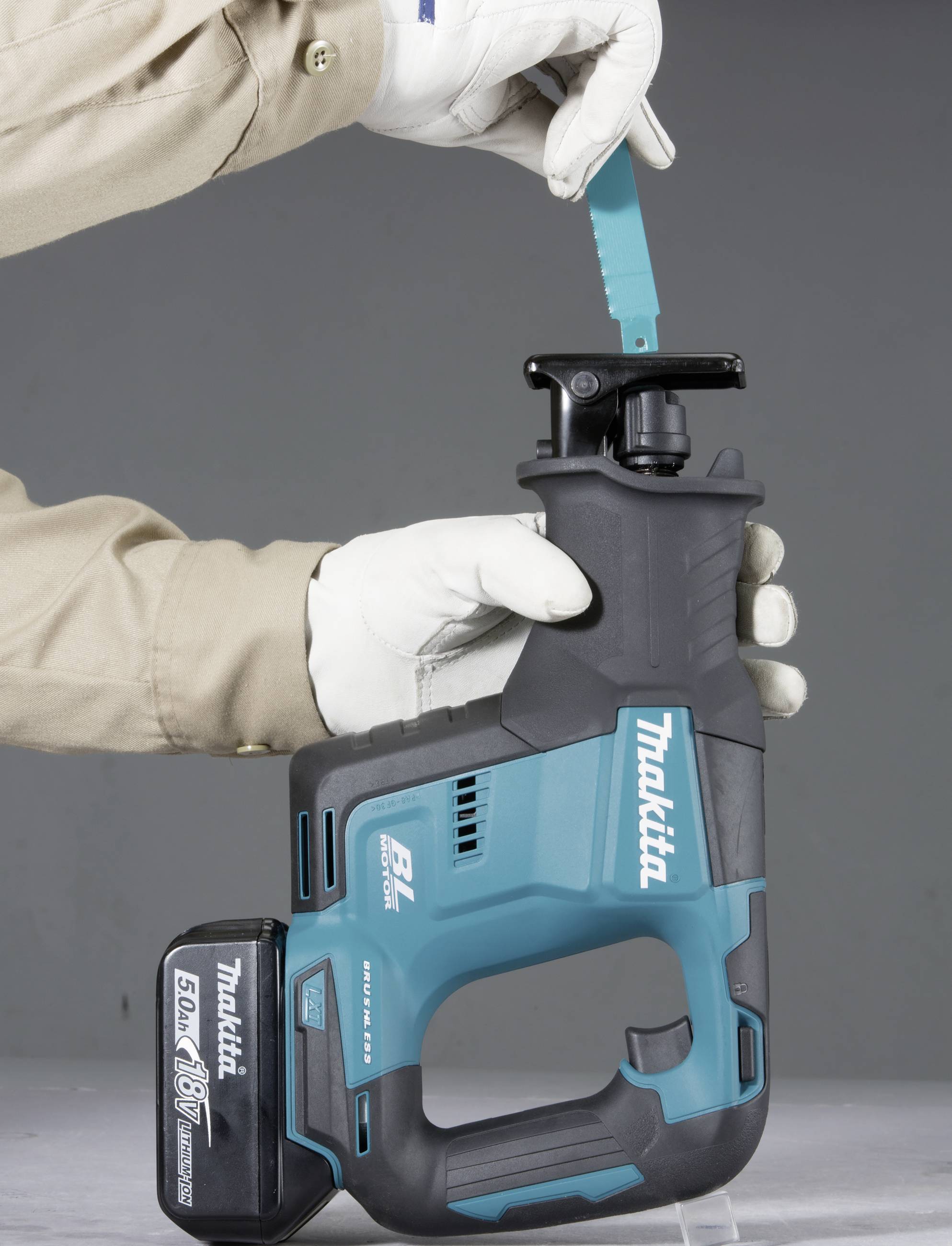 Person in Arbeitskleidung wechselt das Sägeblatt einer blauen Akku-Säbelsäge.