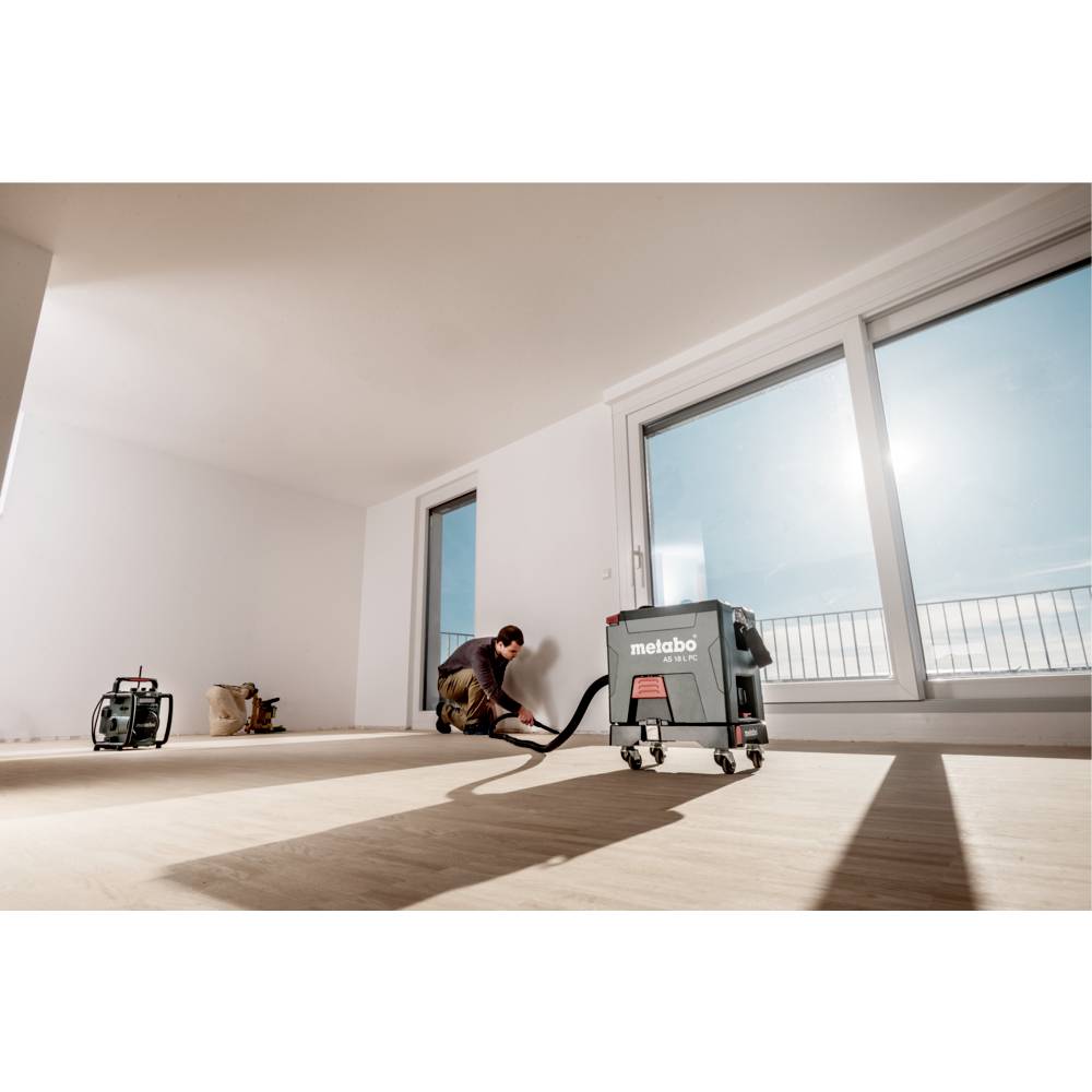 Ein grüner Metabo AS 18 L PC Staubsauger mit kompakter Kastenform, Rädern, Schlauch und Griff, der Mobilität und Design betont.