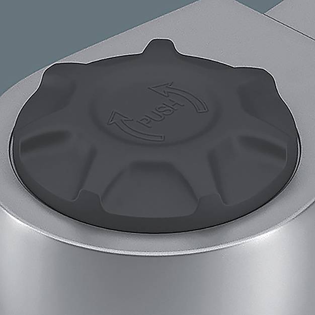 Detailaufnahme eines schwarzen ‚PUSH'-Knopfes auf einem metallischen Gerät, der einen Bedienungsmechanismus andeutet.