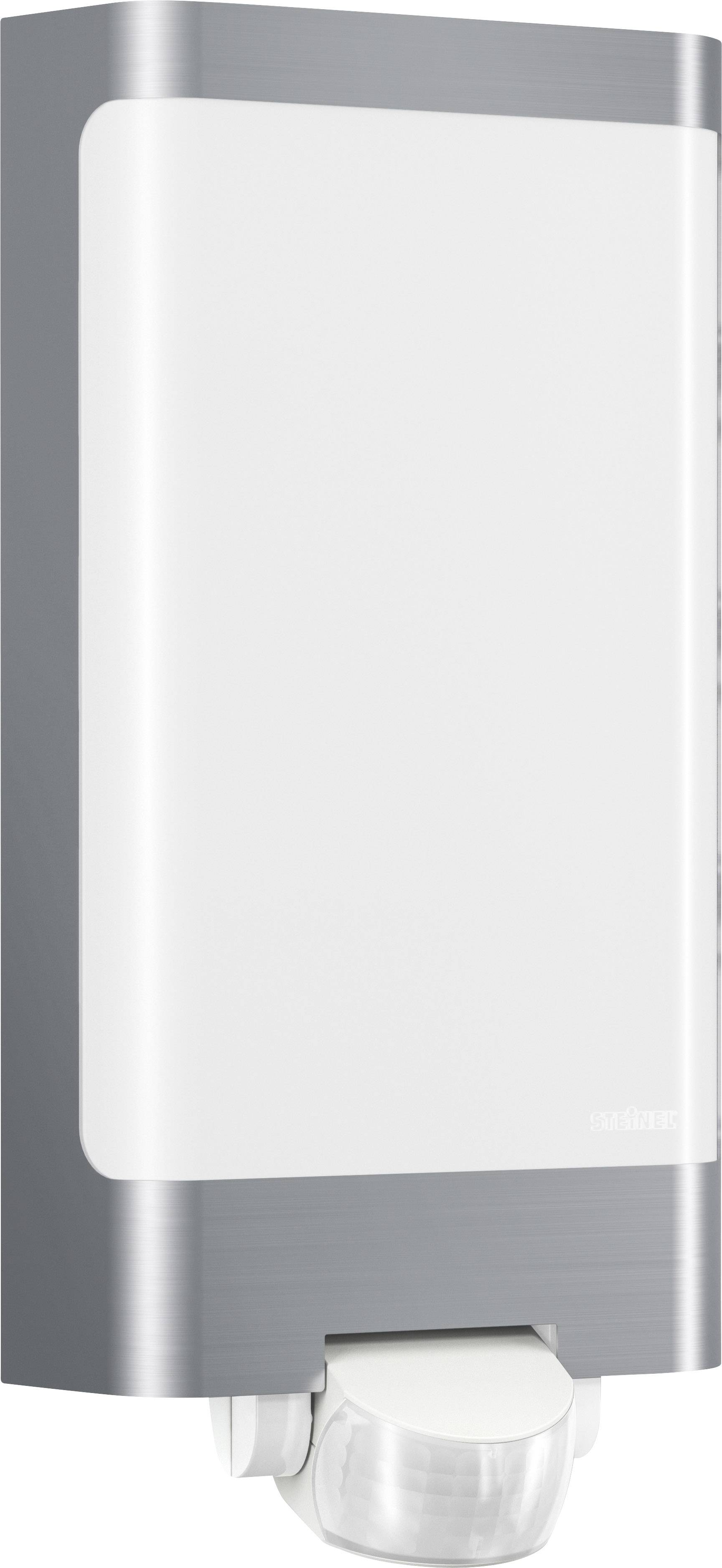 Seifenspender an einer Wand montiert, silbernes und weißes Design, rechteckige Form mit abschließender Öffnung unten für Seifenausgabe.