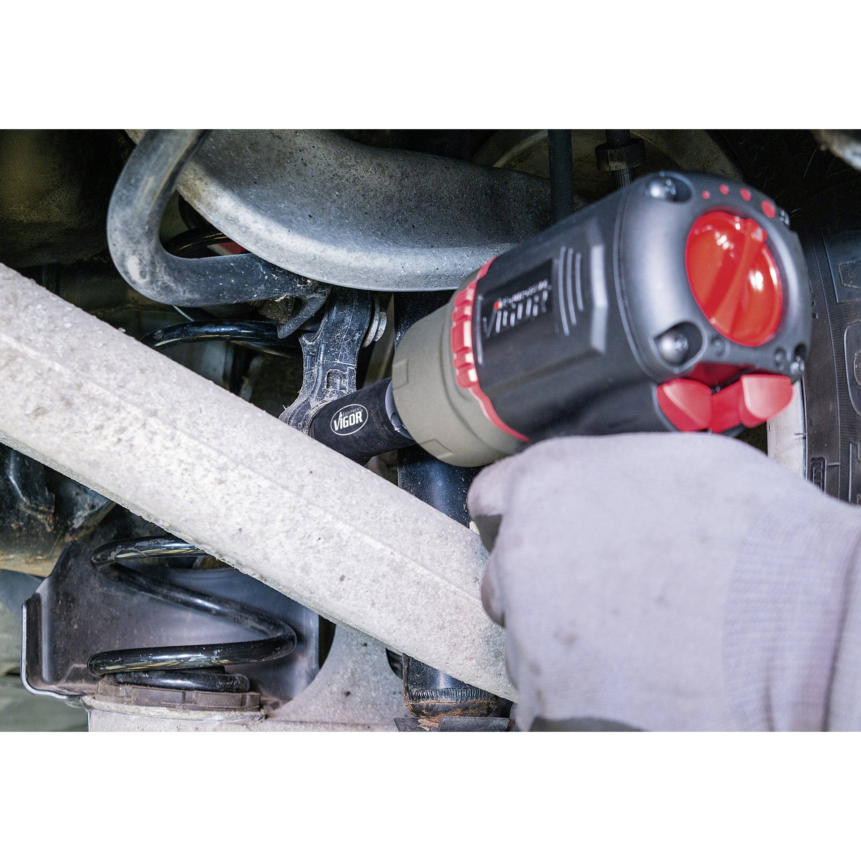 Eine Person verwendet ein Elektrowerkzeug, um eine Schraube an der Fahrzeugaufhängung zu befestigen und dabei Wartungsarbeiten am Fahrgestell zu verrichten.