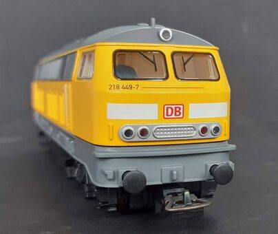 Ein rotes Güterwagen-Zugmodell mit detaillierten Merkmalen, einschließlich Seitenpaneele und Rädern, auf einem Gleis ausgestellt, mit dem Label 'DB' (Deutsche Bahn) gekennzeichnet.