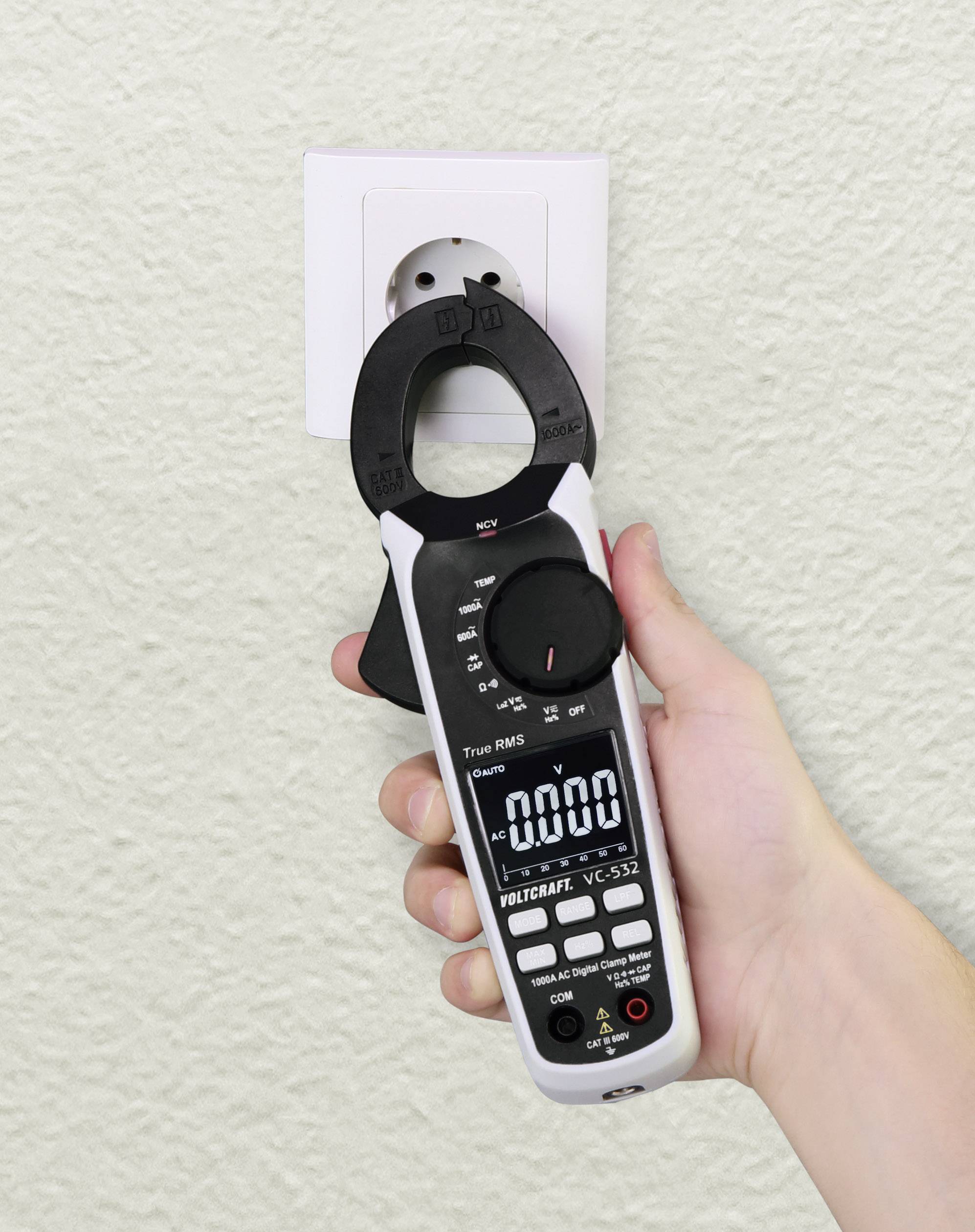 Hand hält ein digitales Multimeter, das auf eine Steckdose gerichtet ist. Das Display zeigt Null, was keinen erfassten Stromfluss anzeigt.