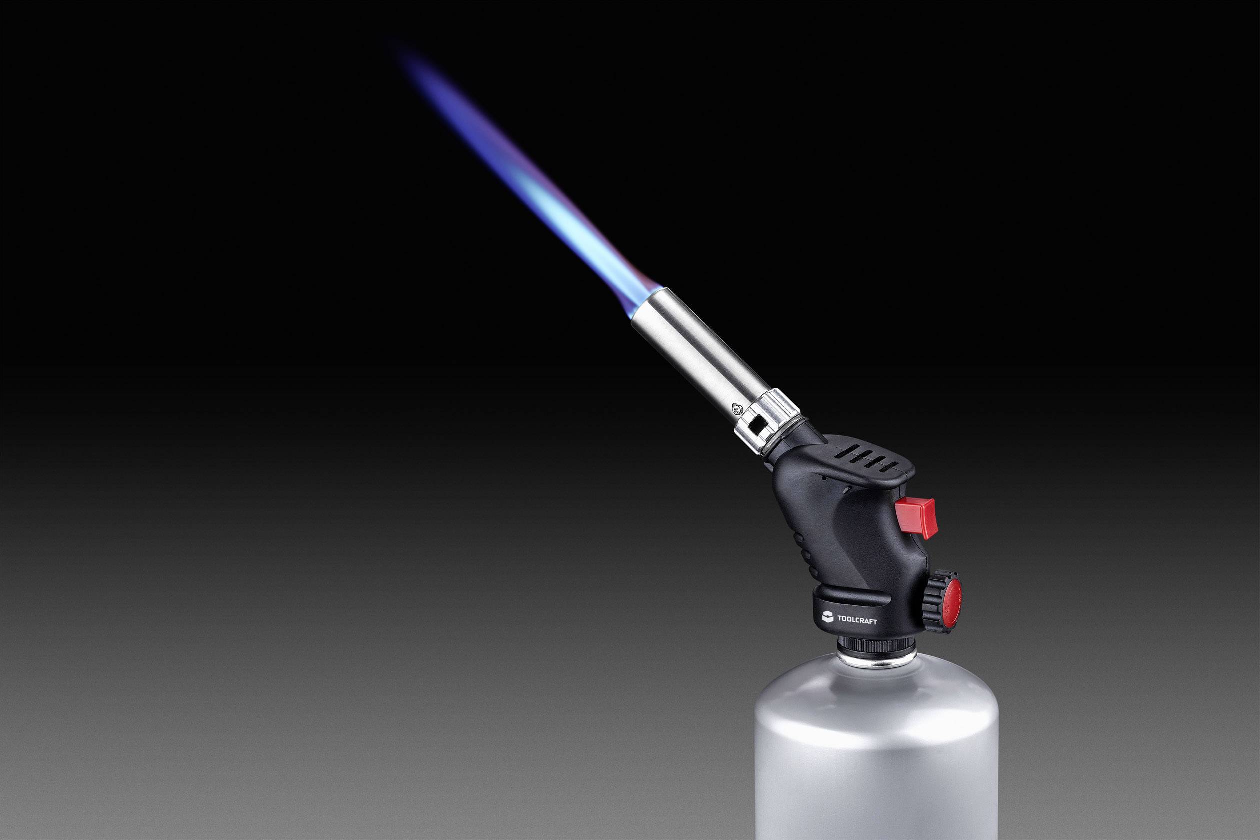Ein tragbarer Bunsenbrenner stößt eine blaue Flamme aus. Der Brenner hat einen roten Einstellknopf und sitzt auf einer Metallkartusche.