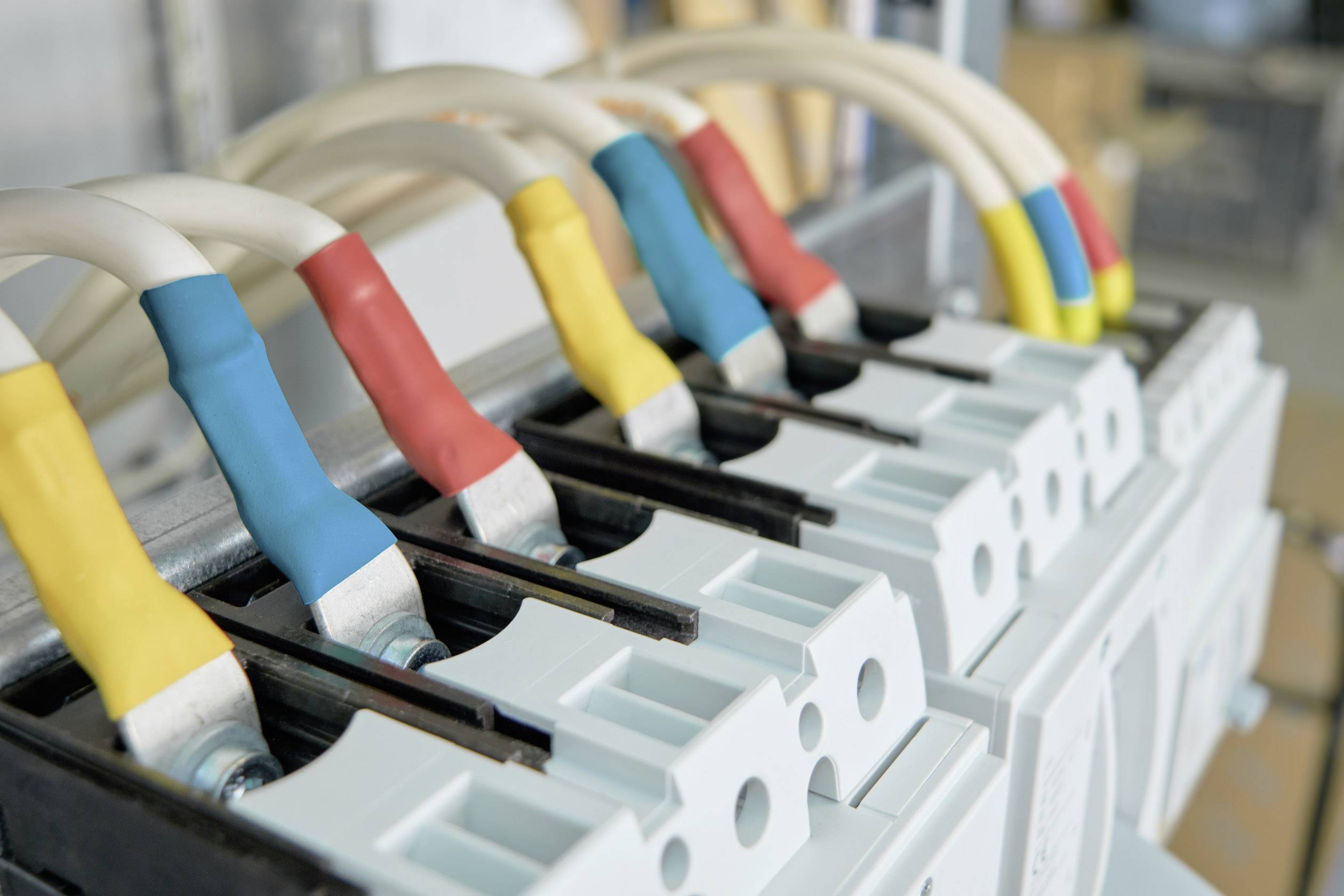 Stromkabel in verschiedenen Farben sind an Elektroanschlüsse angeschlossen. Sie repräsentieren unterschiedliche Phasen oder Leitungen.