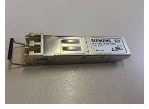 Ein Siemens SFP-Modul liegt auf einem Tisch. Es dient zur Verbindung von Netzwerkgeräten und ist rechteckig mit Metallgehäuse.